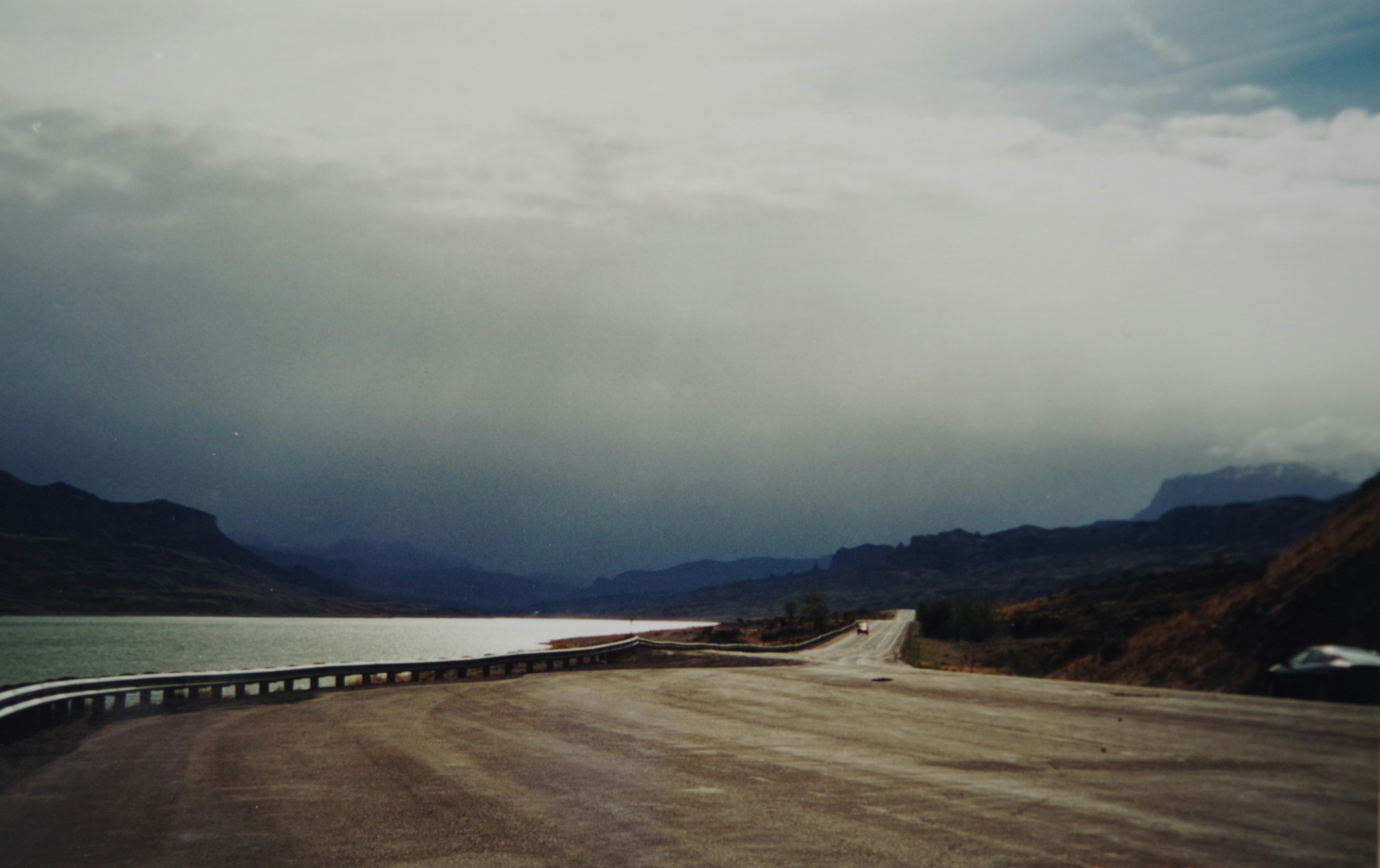 Route sinueuse près d'un lac avec des nuages sombres