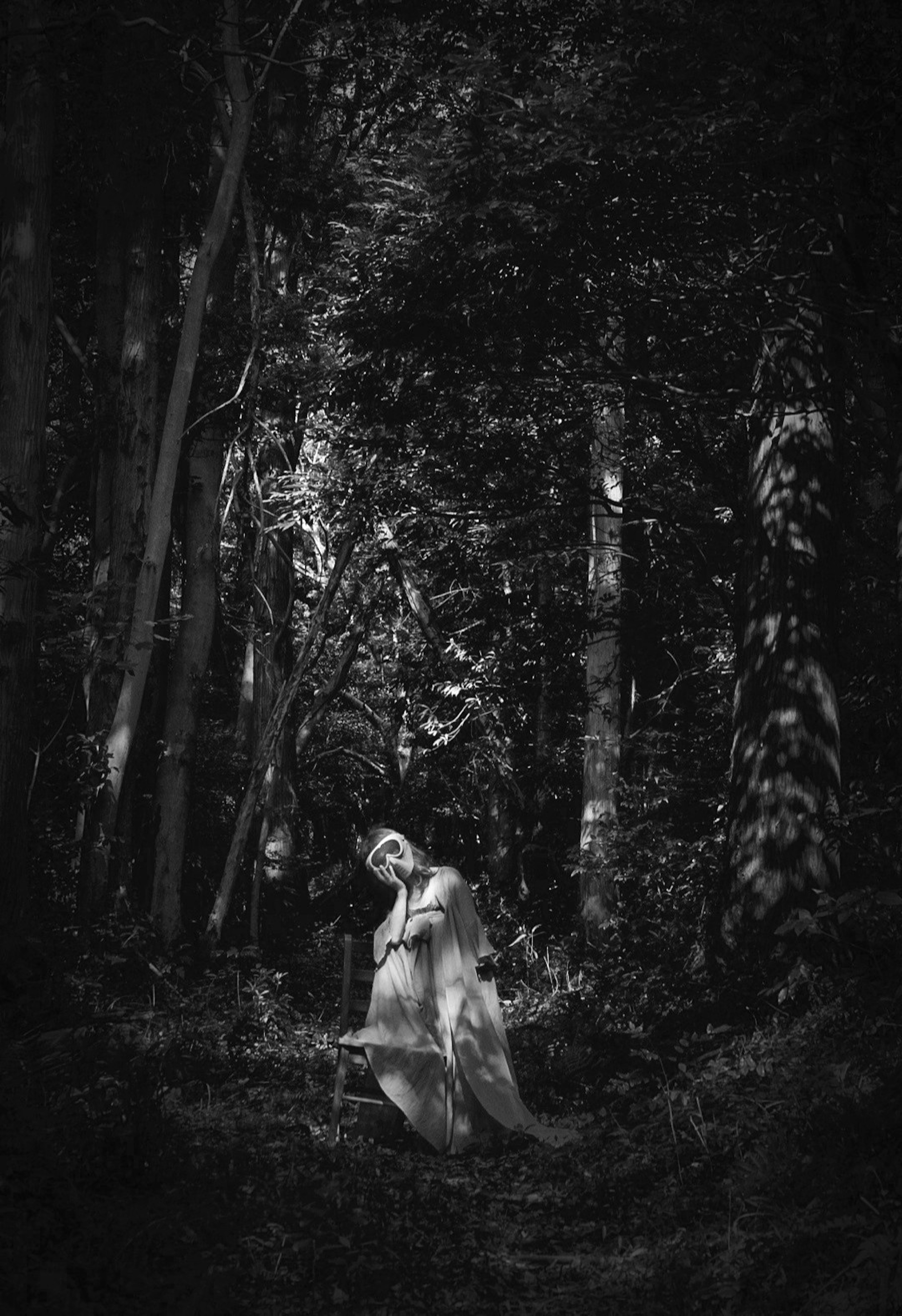 Una donna in abito bianco si trova in una foresta scura