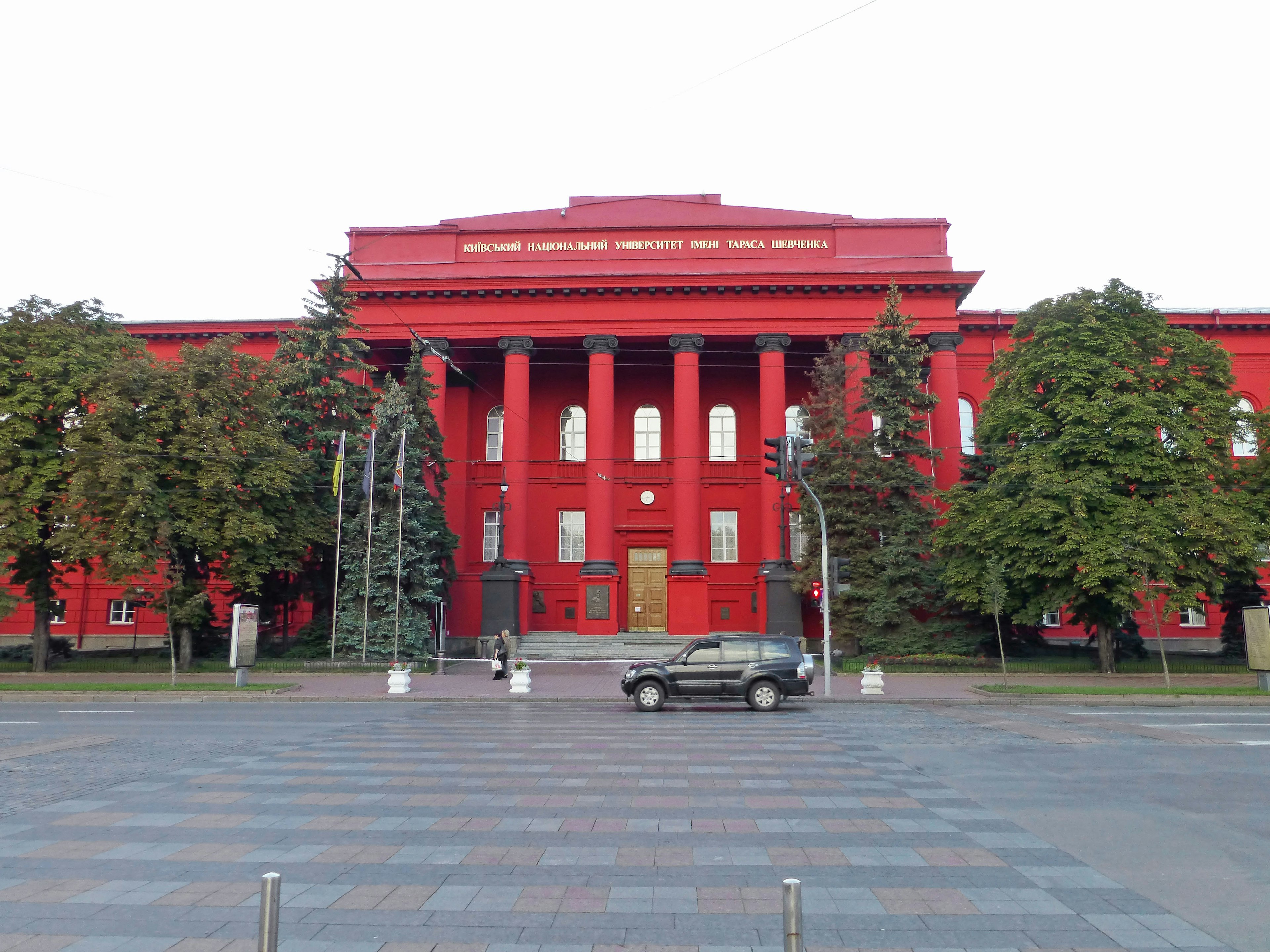 Bâtiment rouge avec des colonnes et des arbres verts environnants