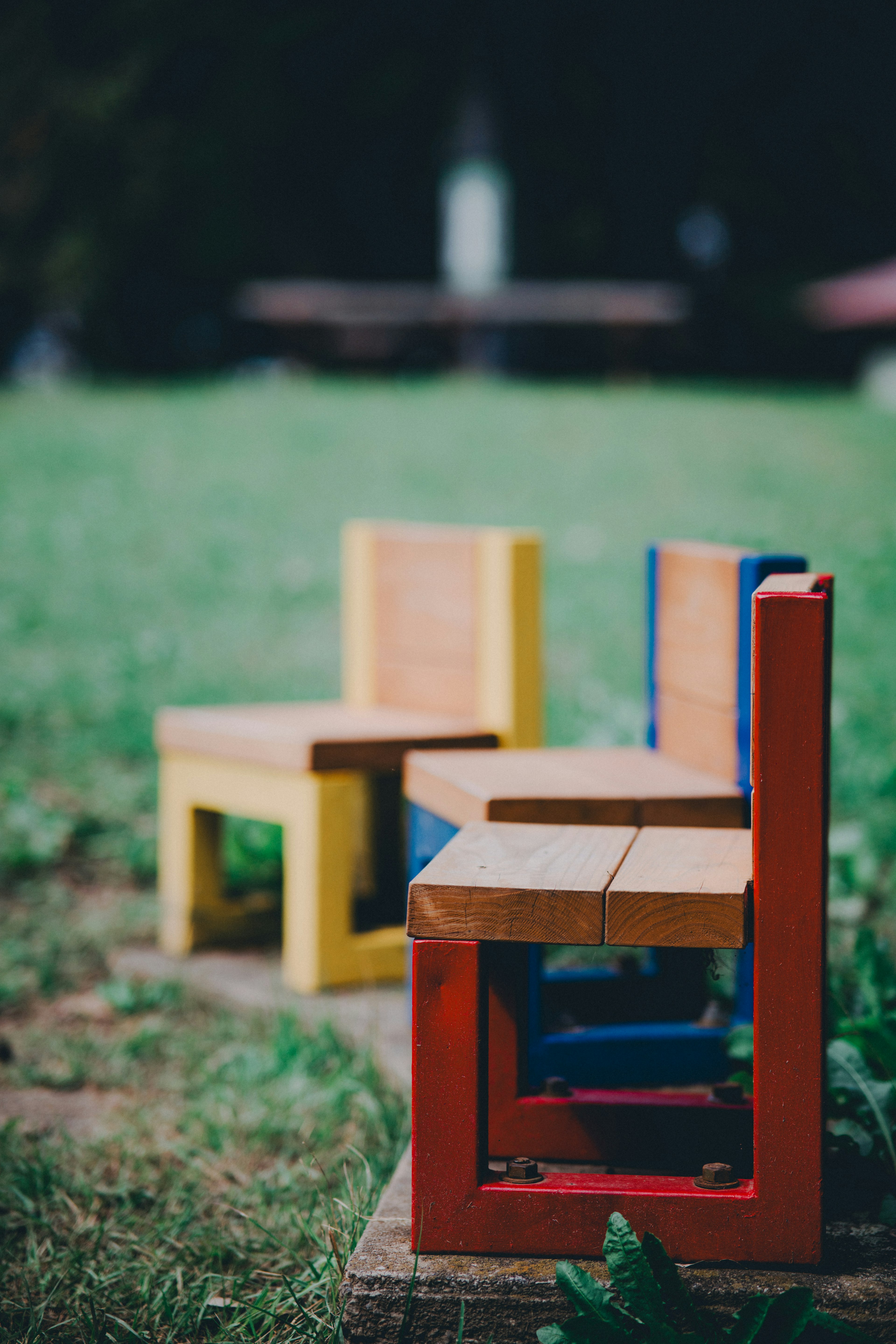 Chaises en bois colorées placées sur de l'herbe