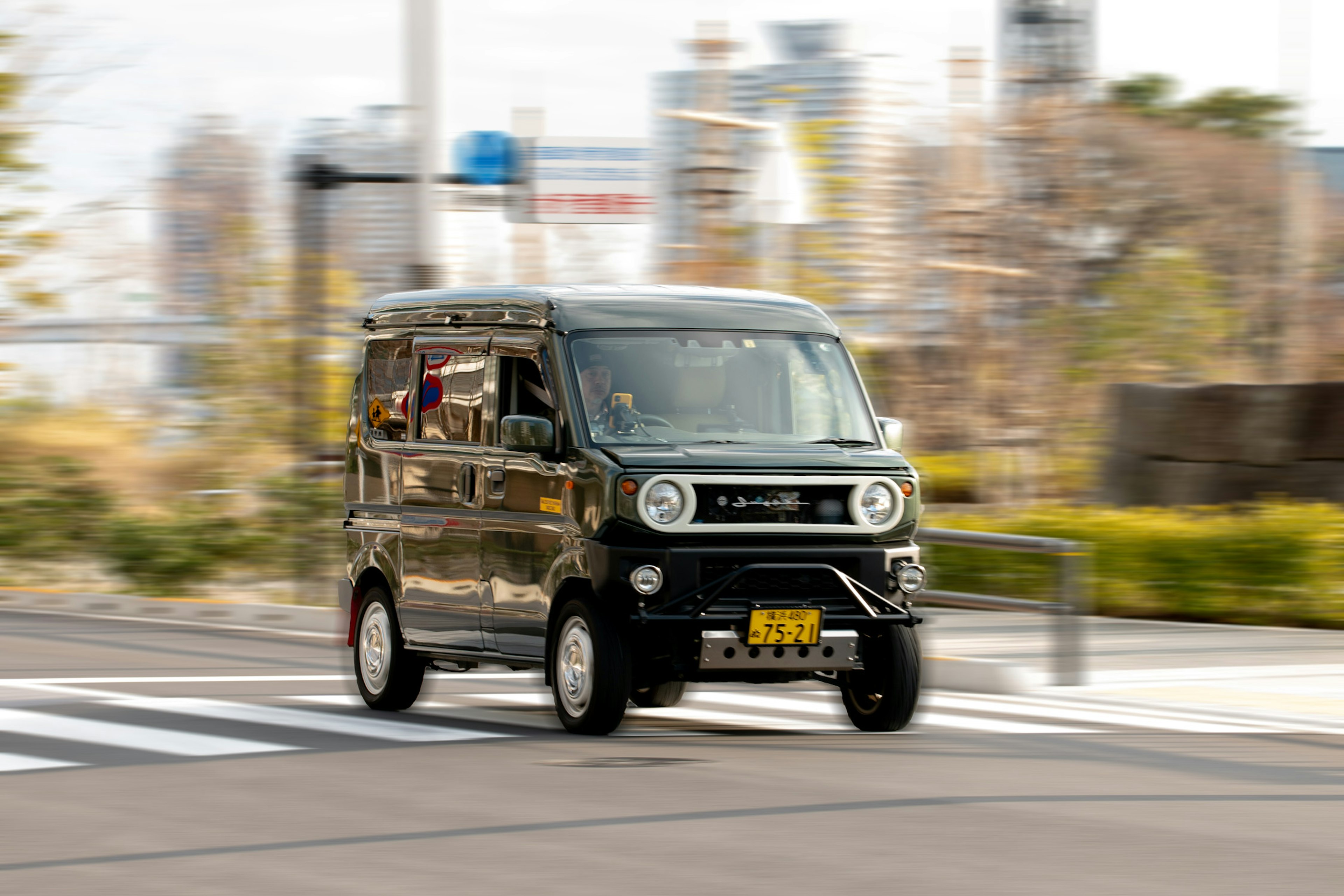 黒い軽自動車が交差点を走る風景