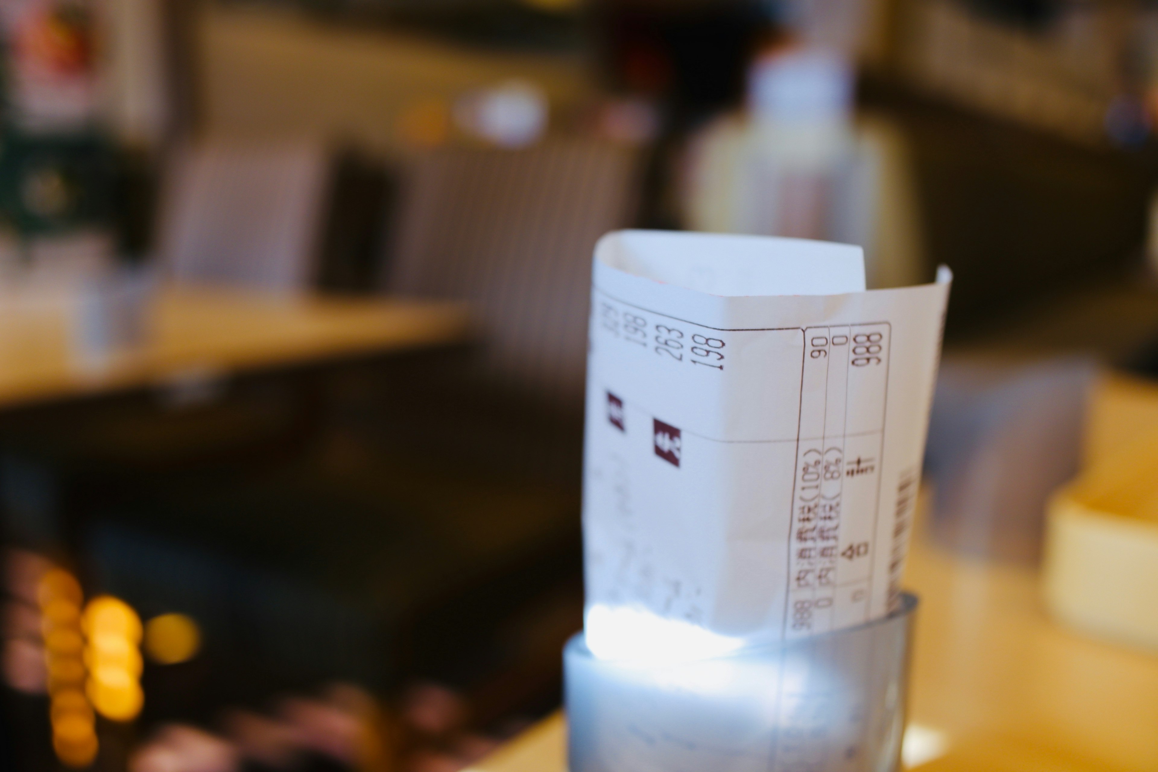 A receipt standing on a table with a blurred background of chairs and tables