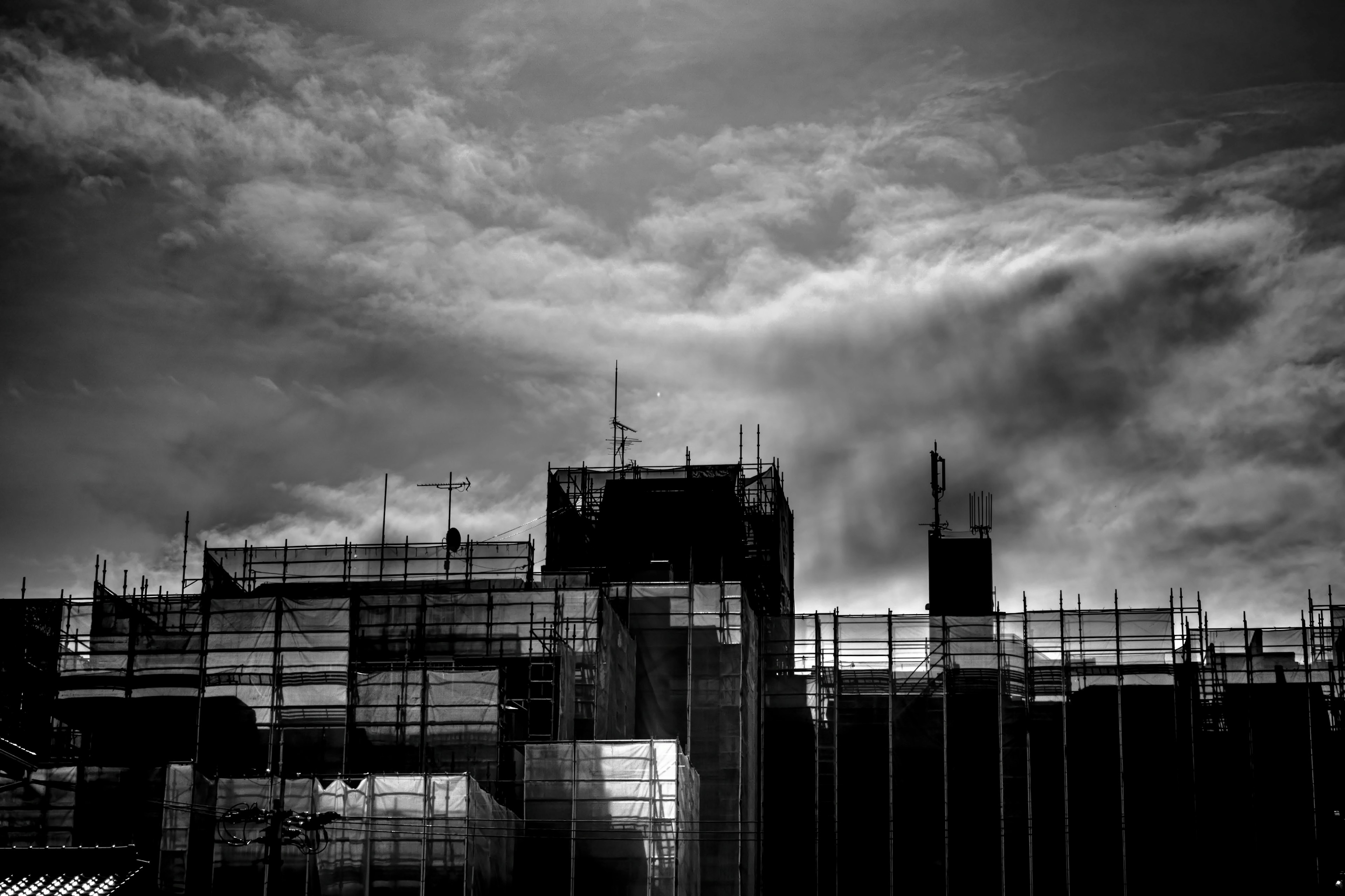 Silhouette of a building under construction with dark clouds