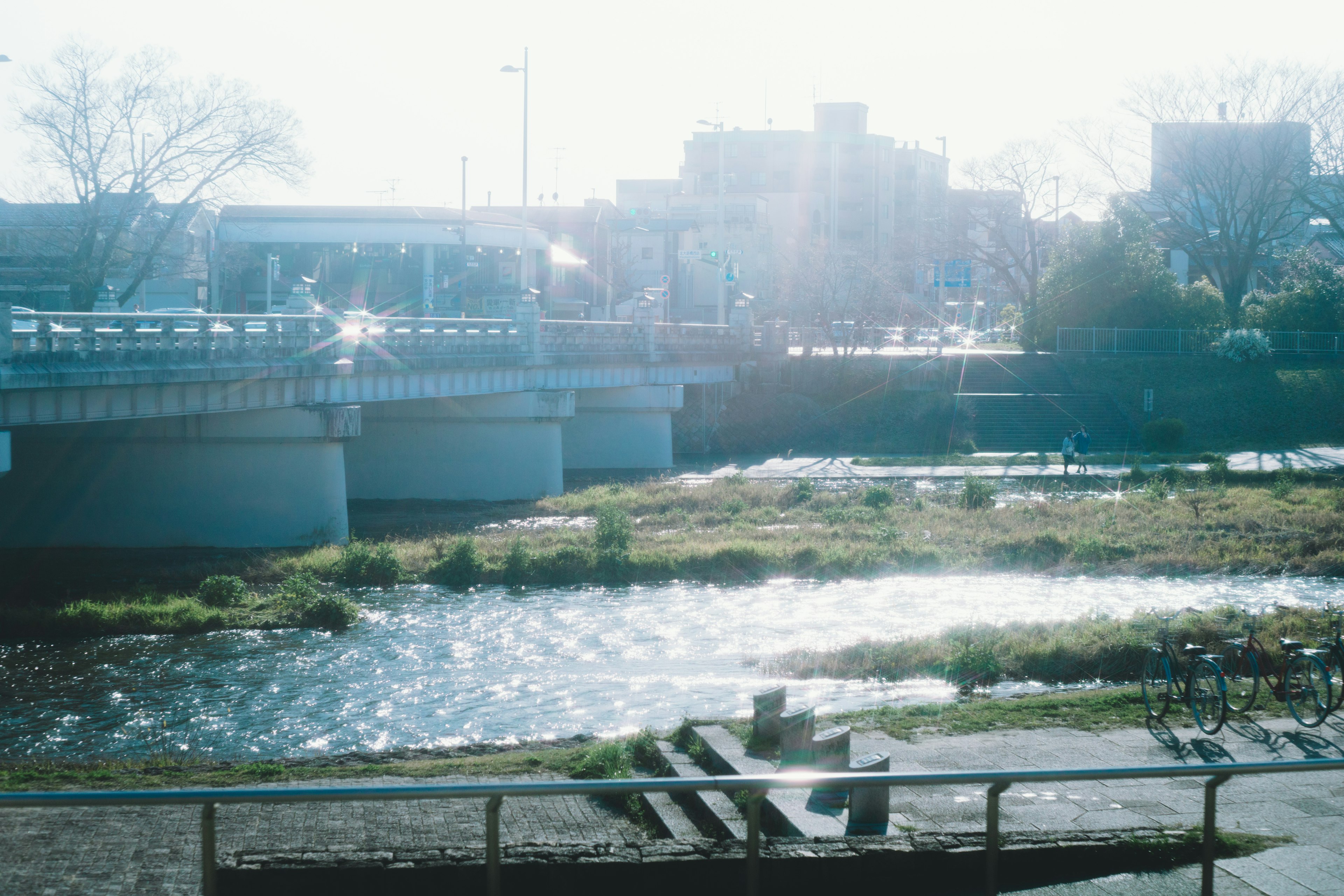 Landschaftsansicht eines Flusses und einer Brücke mit Sonnenlicht, das sich auf dem Wasser spiegelt