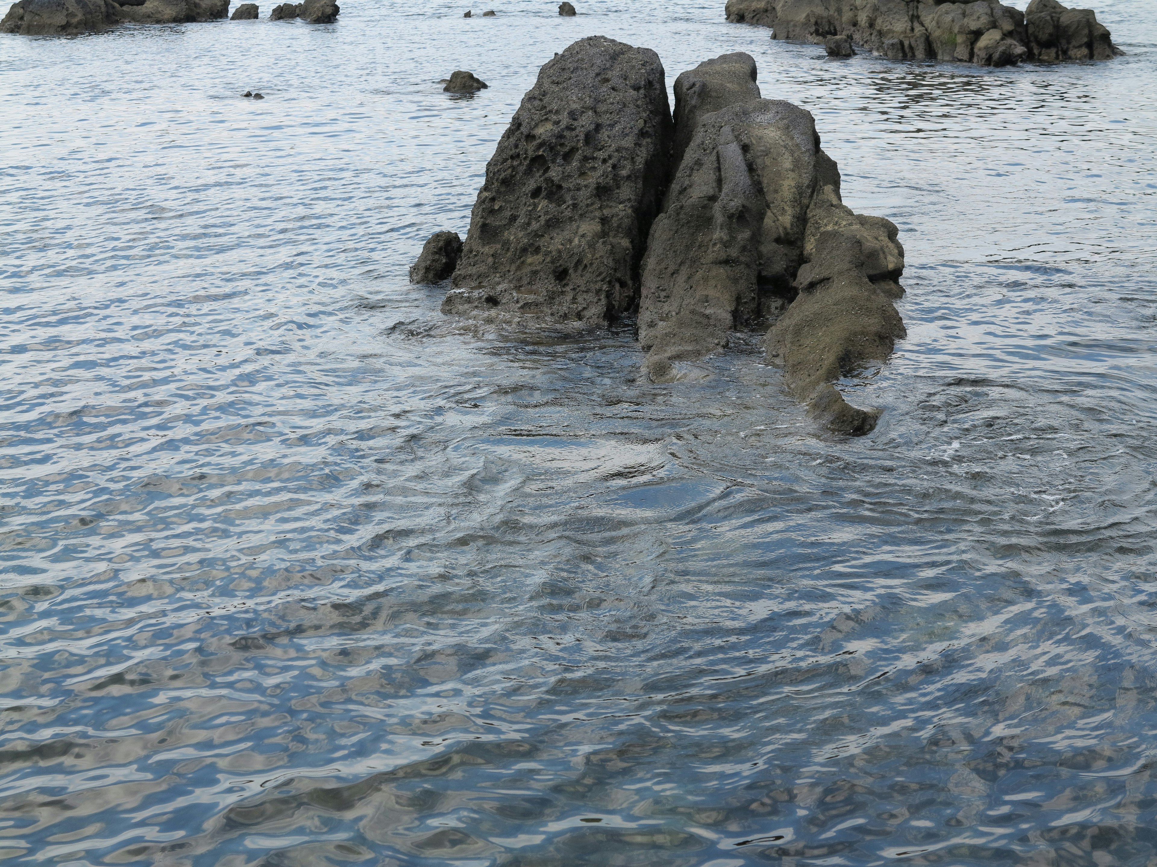 Rocks partially submerged in calm water with gentle ripples