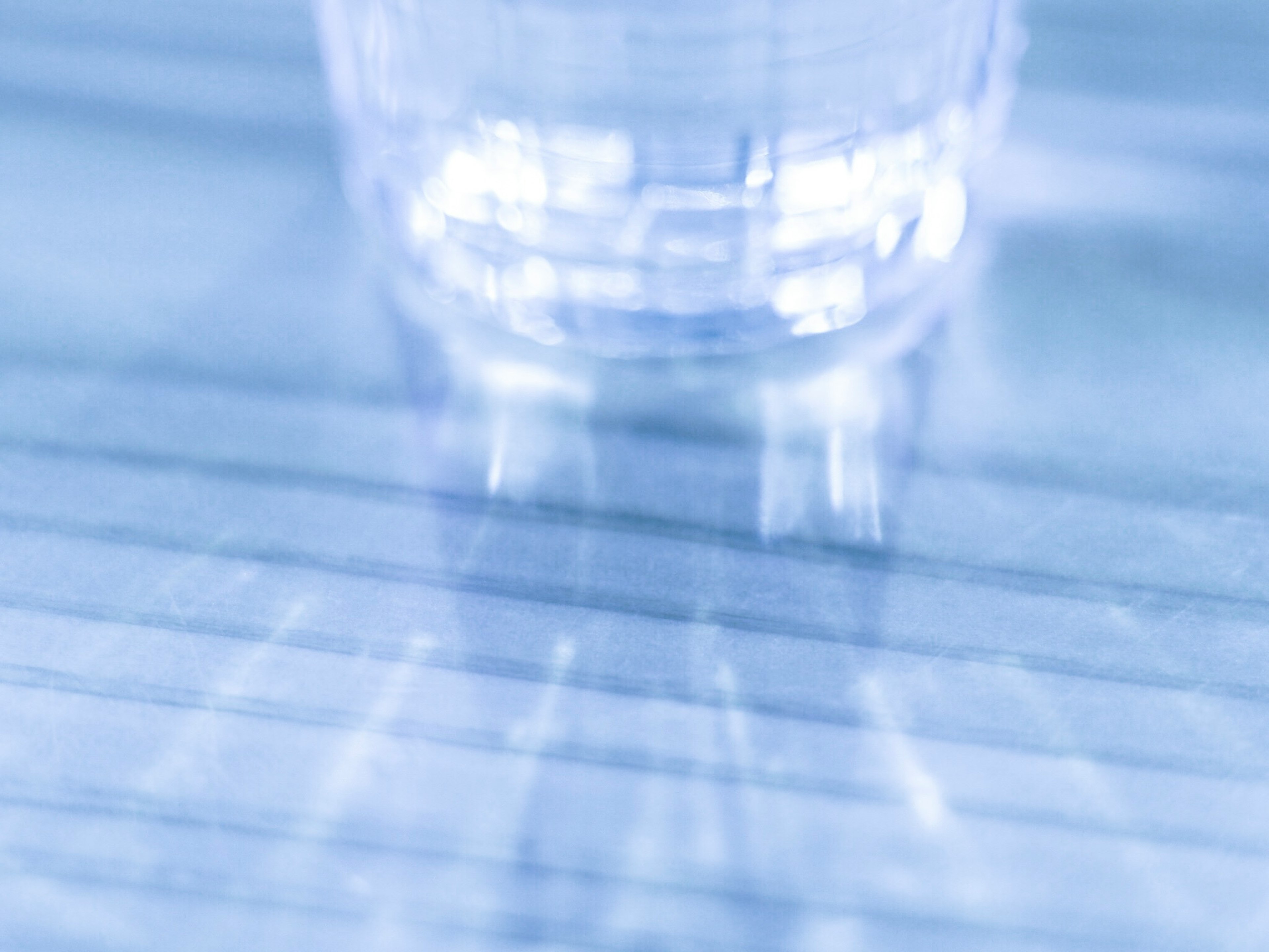 Blurred transparent glass of water with reflections on a blue background