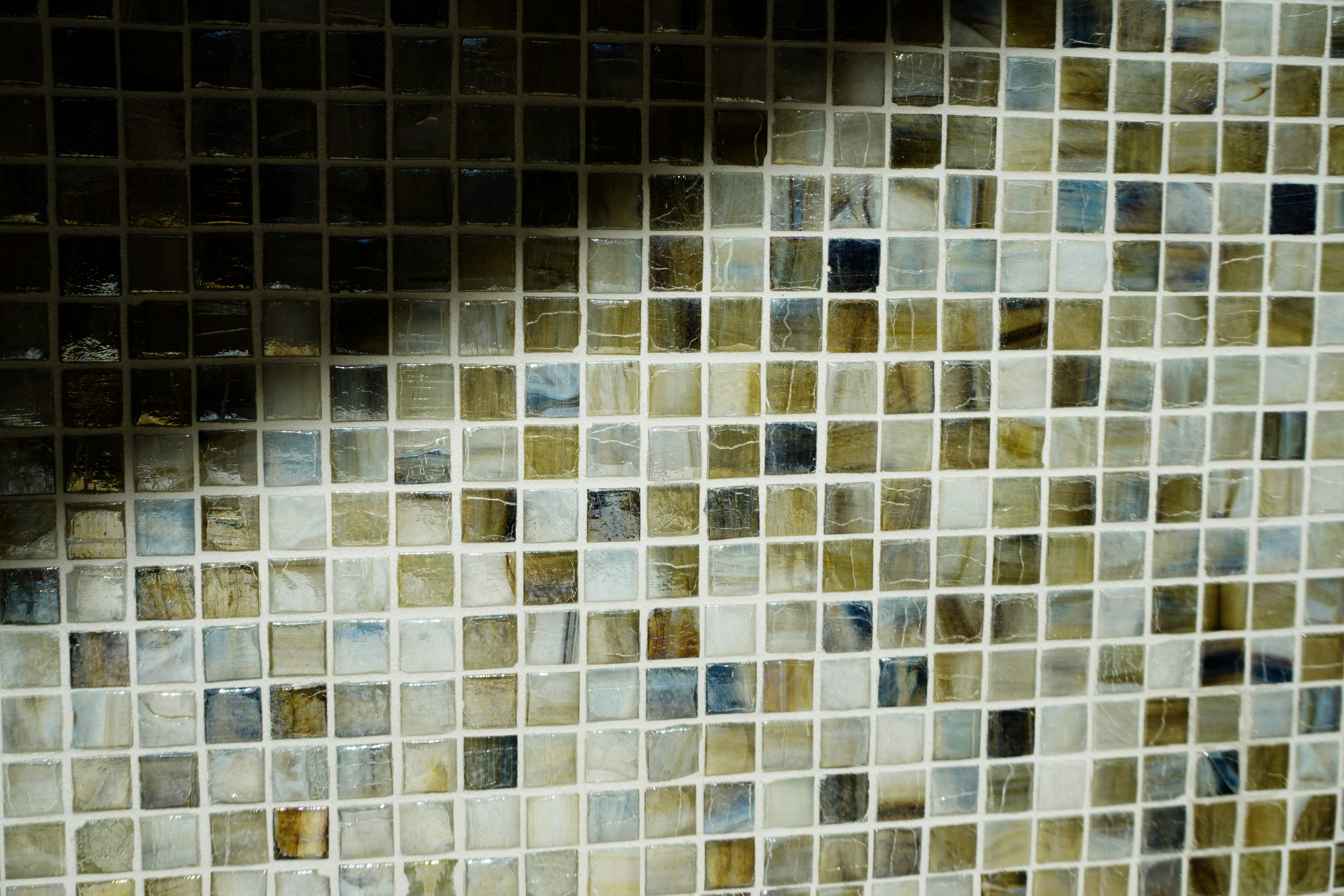 Image d'un mur en mosaïque avec de petites tuiles de différentes nuances de beige et de gris