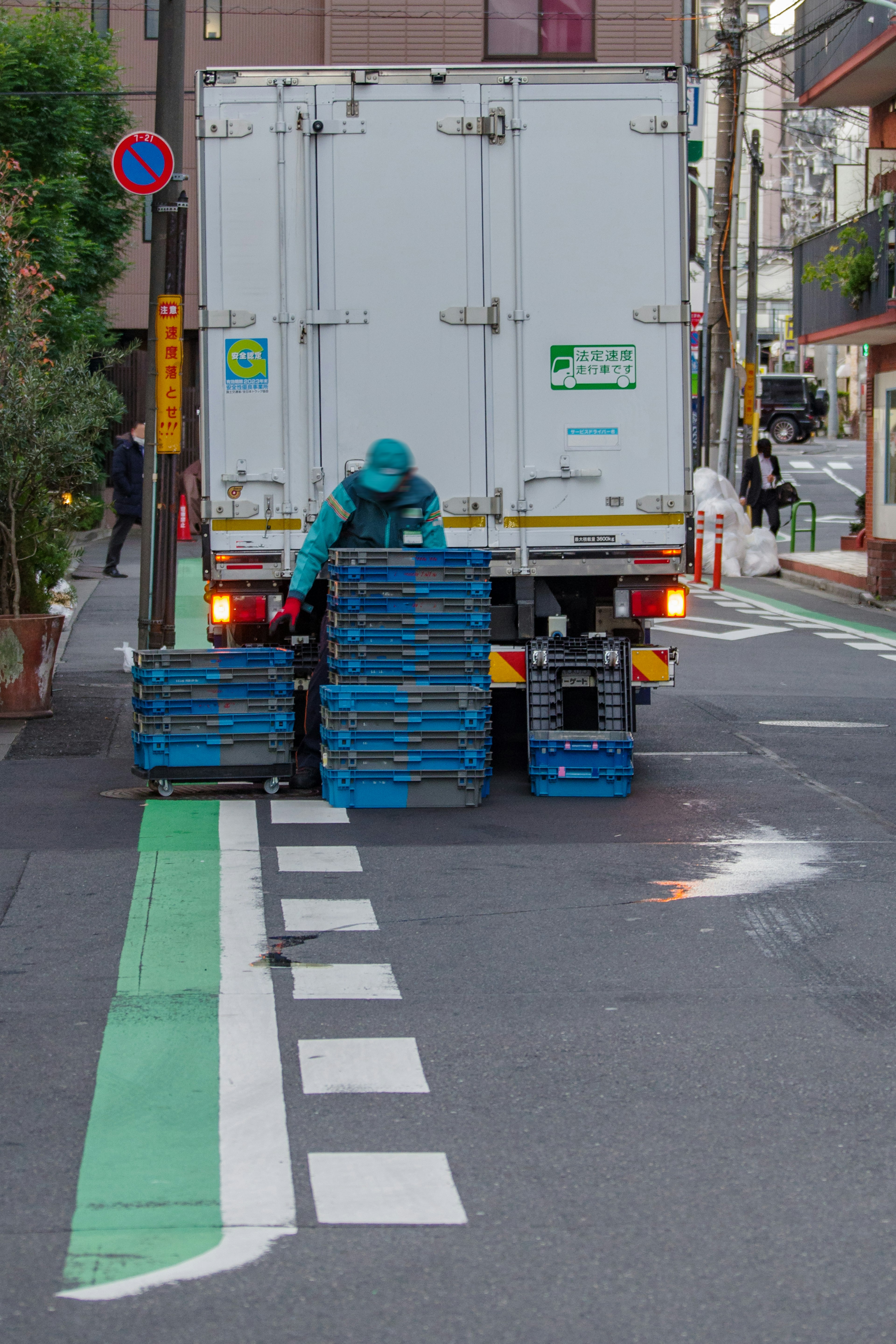 Una scena di strada con un camion e pallet blu impilati sul retro