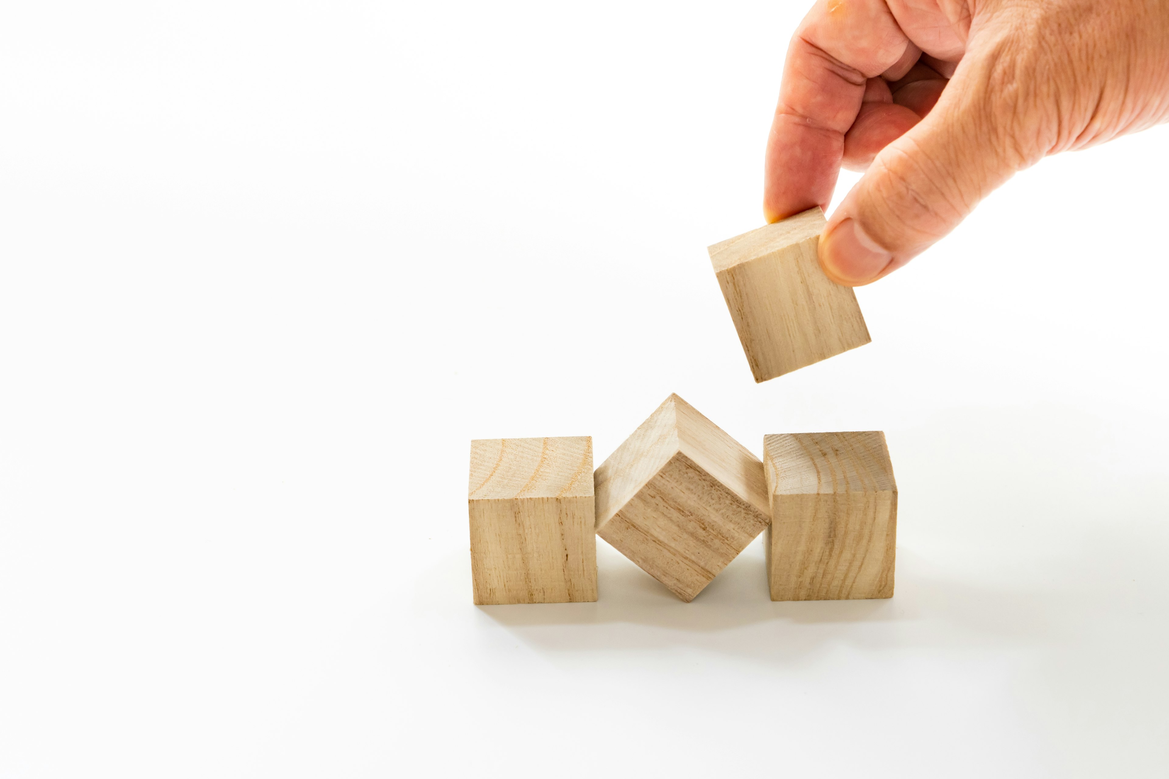 A hand placing a wooden block on top of other wooden blocks