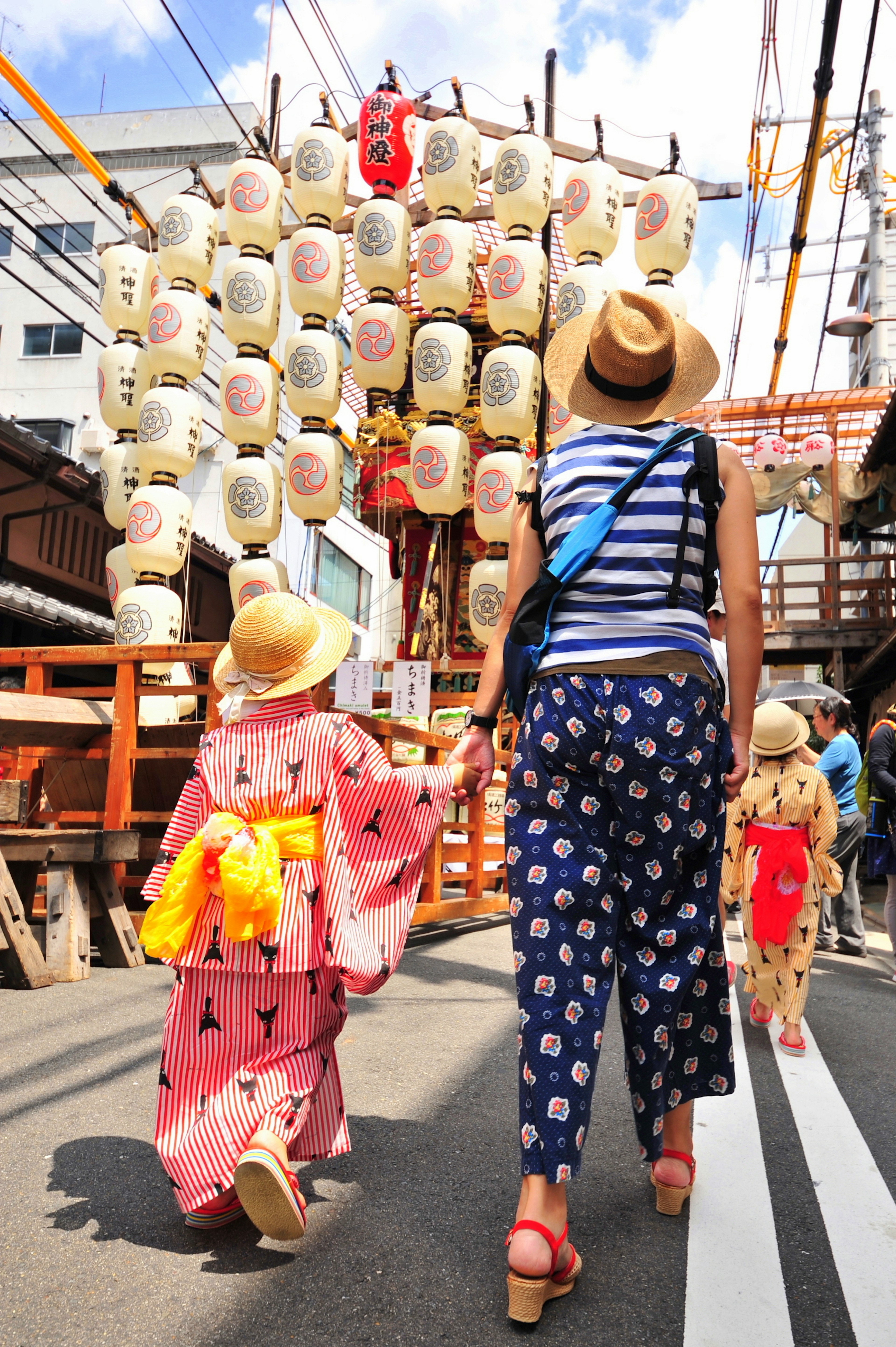 Una donna e un bambino che camminano in abiti tradizionali sotto lanterne da festival