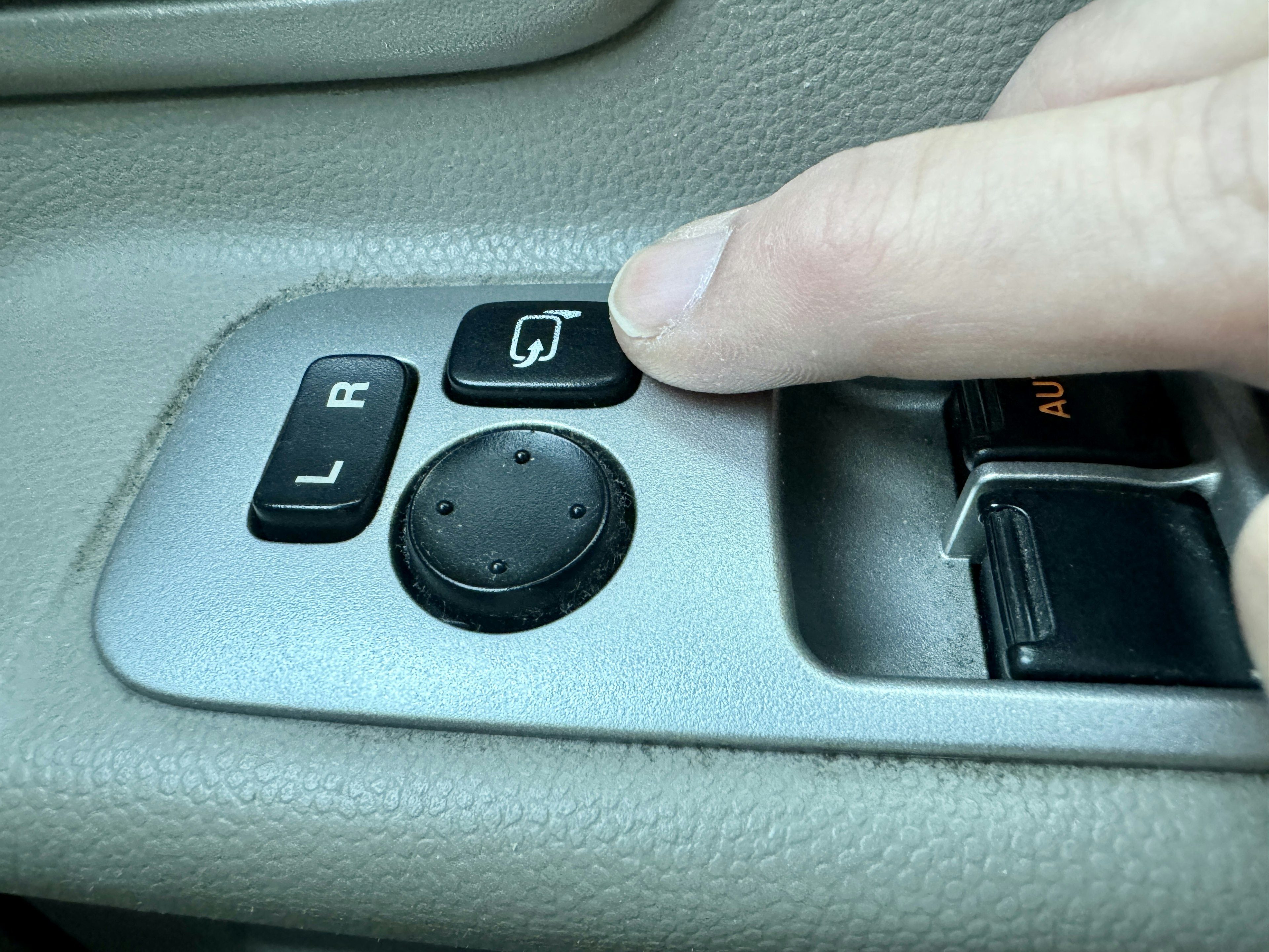 A hand pressing a window control button in a car