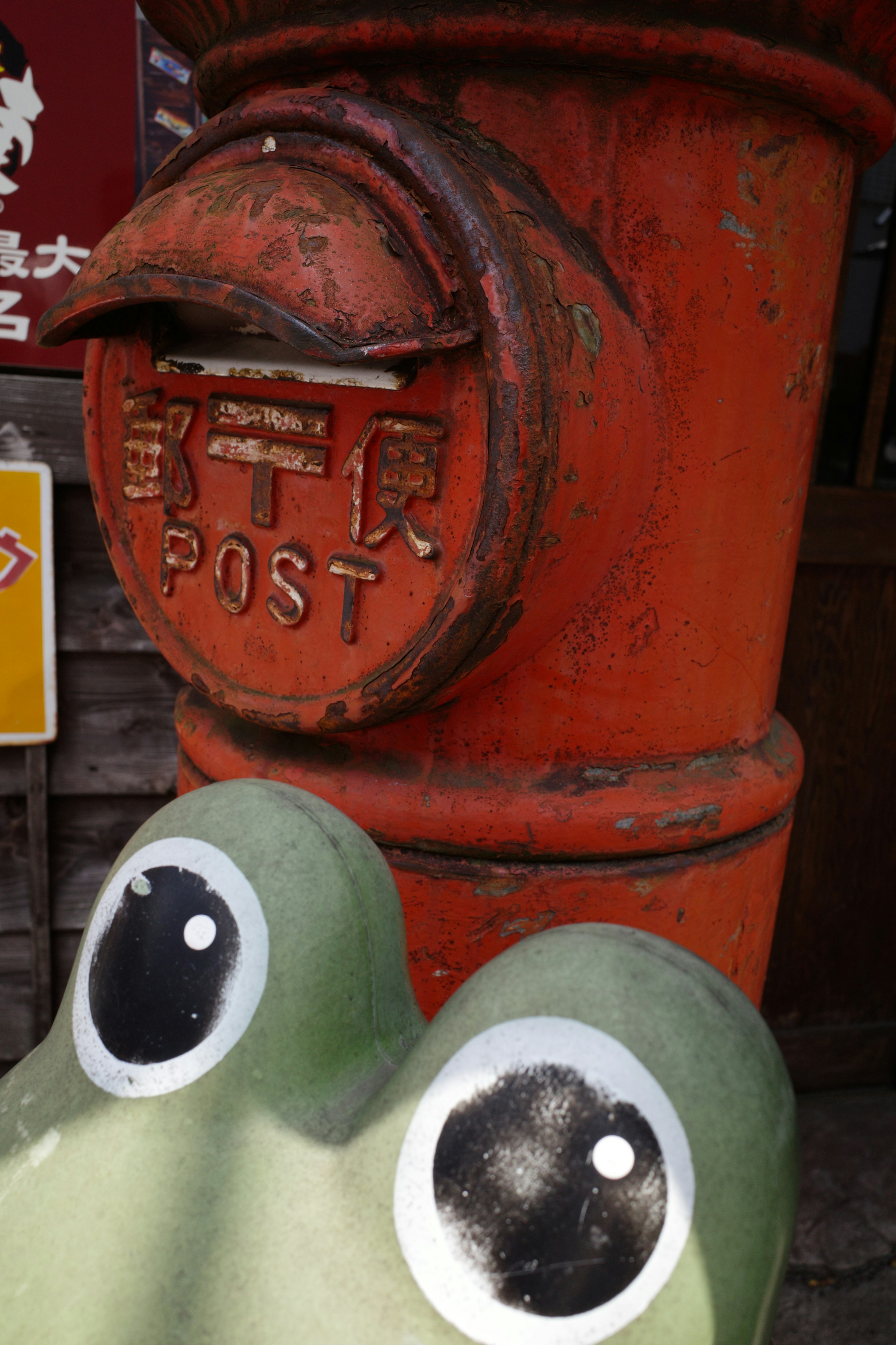 Gros plan sur une boîte aux lettres rouge et une statue de grenouille