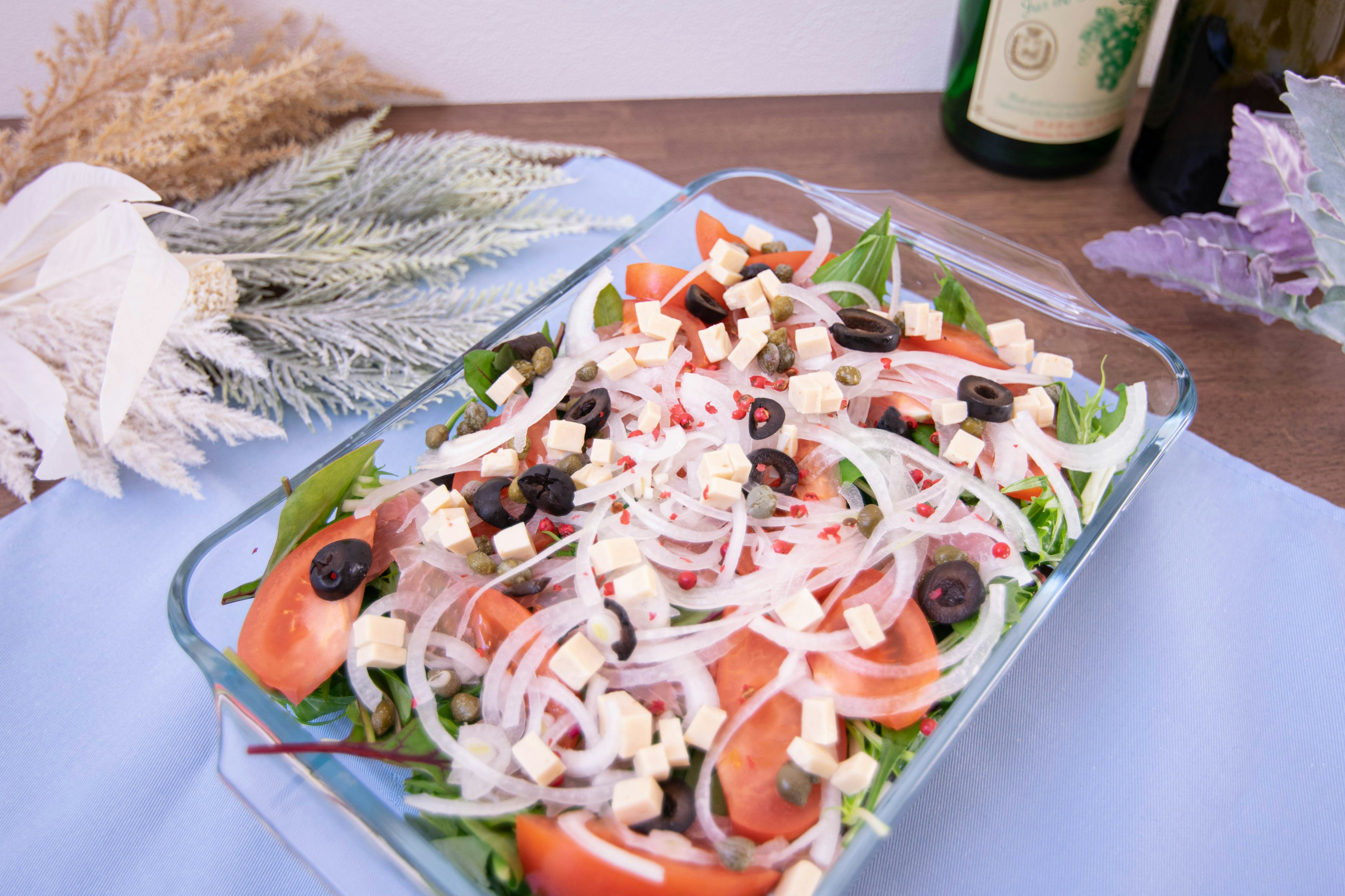 Un'insalata fresca in un piatto di vetro guarnita con pomodori, olive e formaggio