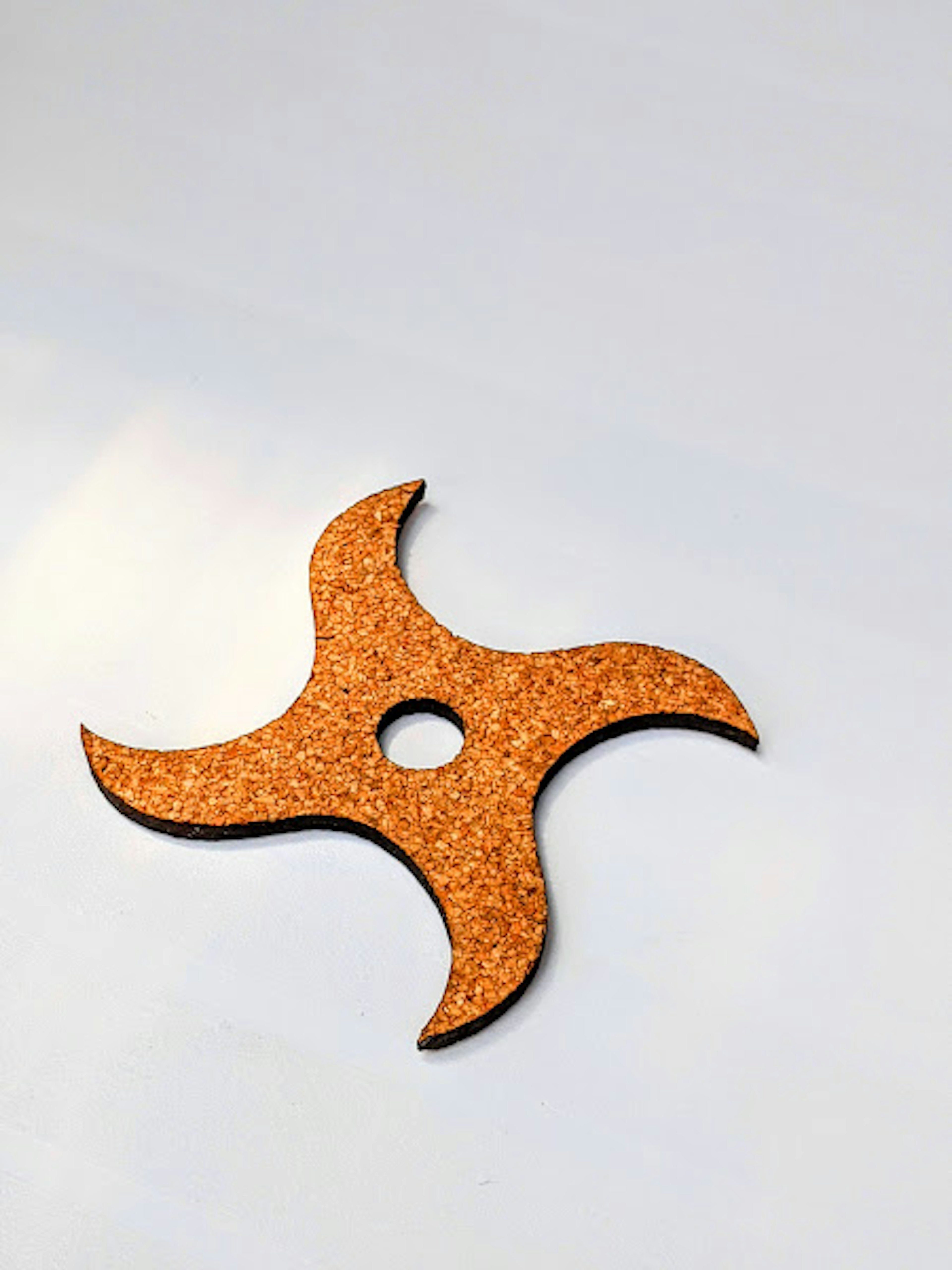 A cork ninja star shaped object placed on a white background