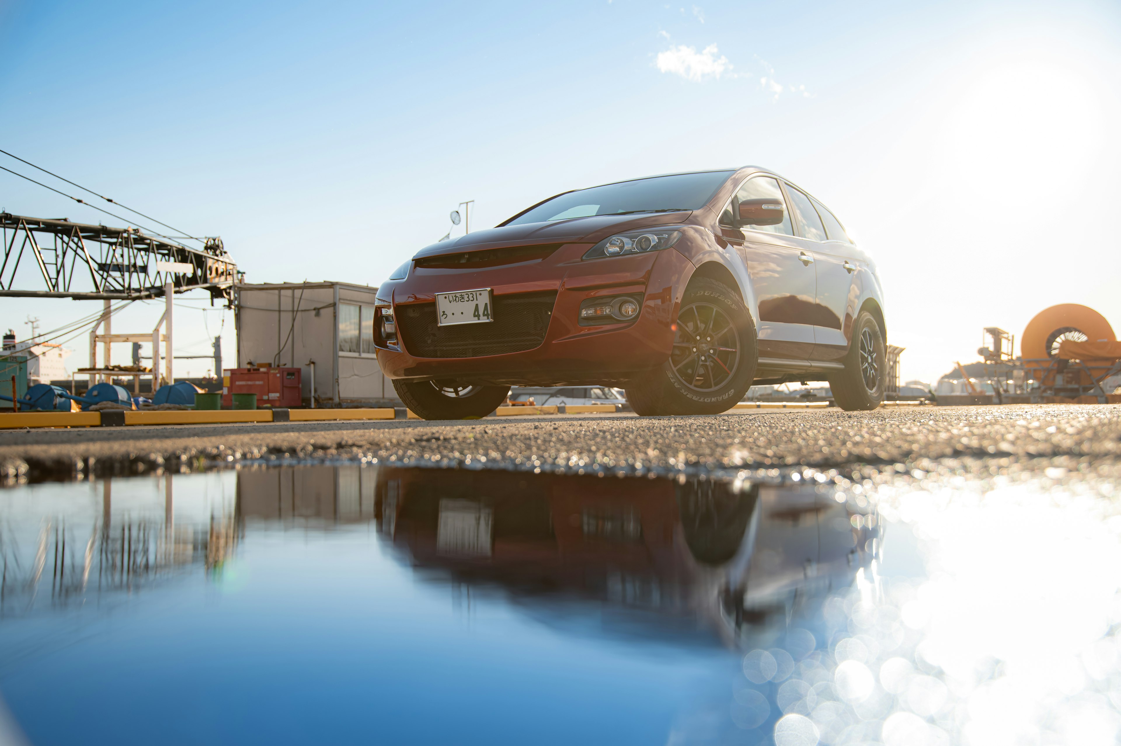 Roter SUV, der in einer industriellen Umgebung neben einer Pfütze parkt