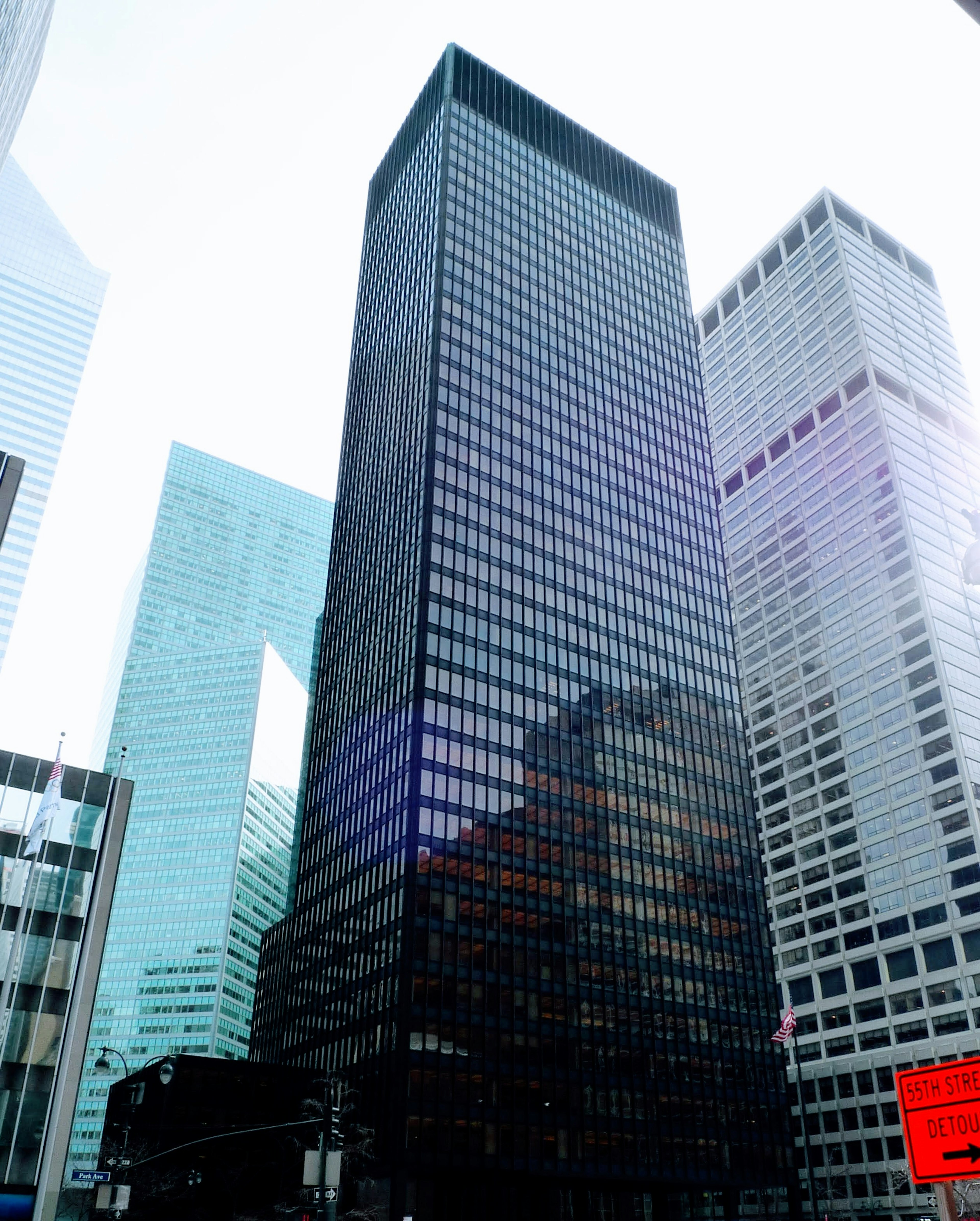 Grand bâtiment en verre noir entouré d'autres gratte-ciels