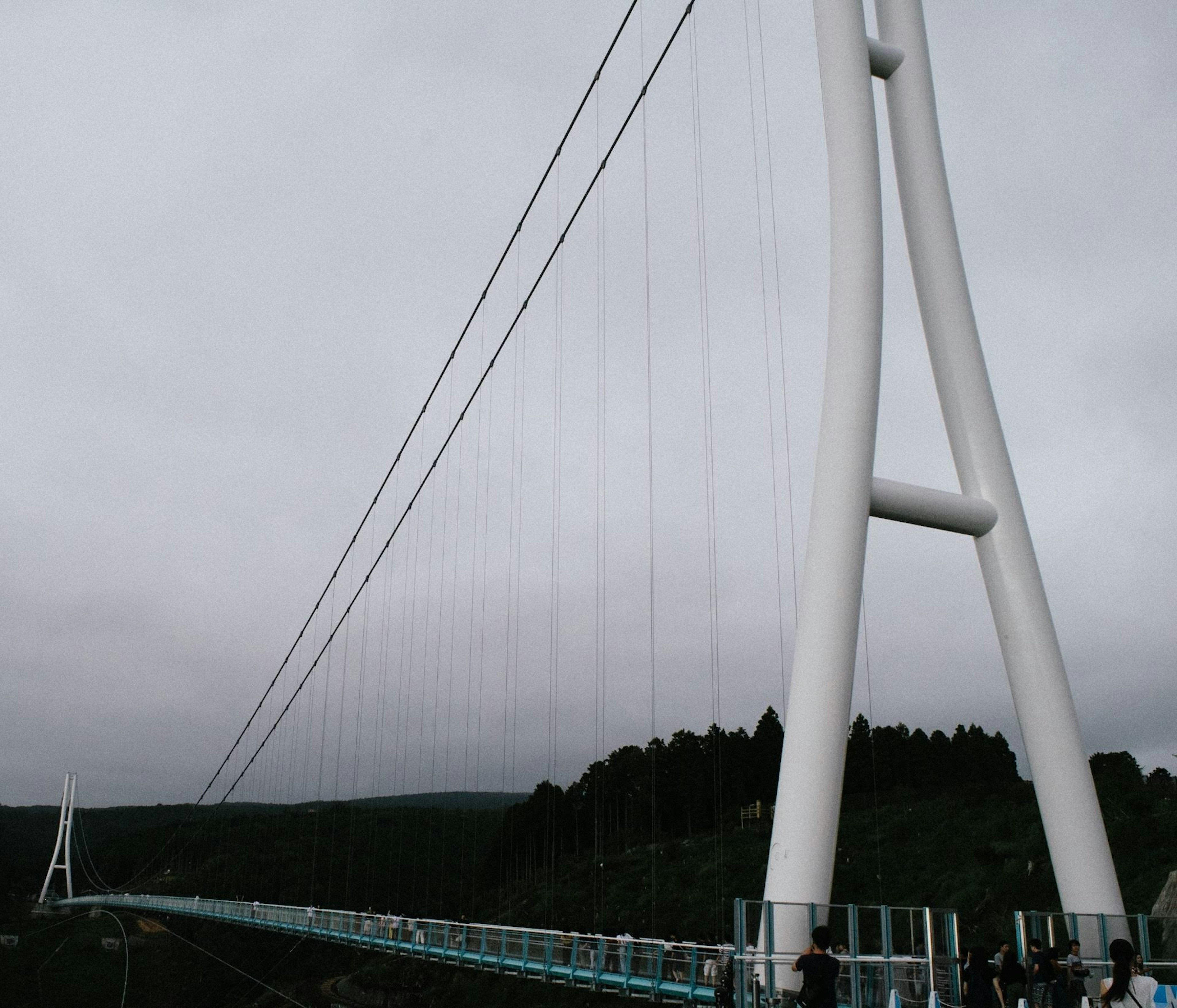 Eine weiße Hängebrücke unter einem bewölkten Himmel