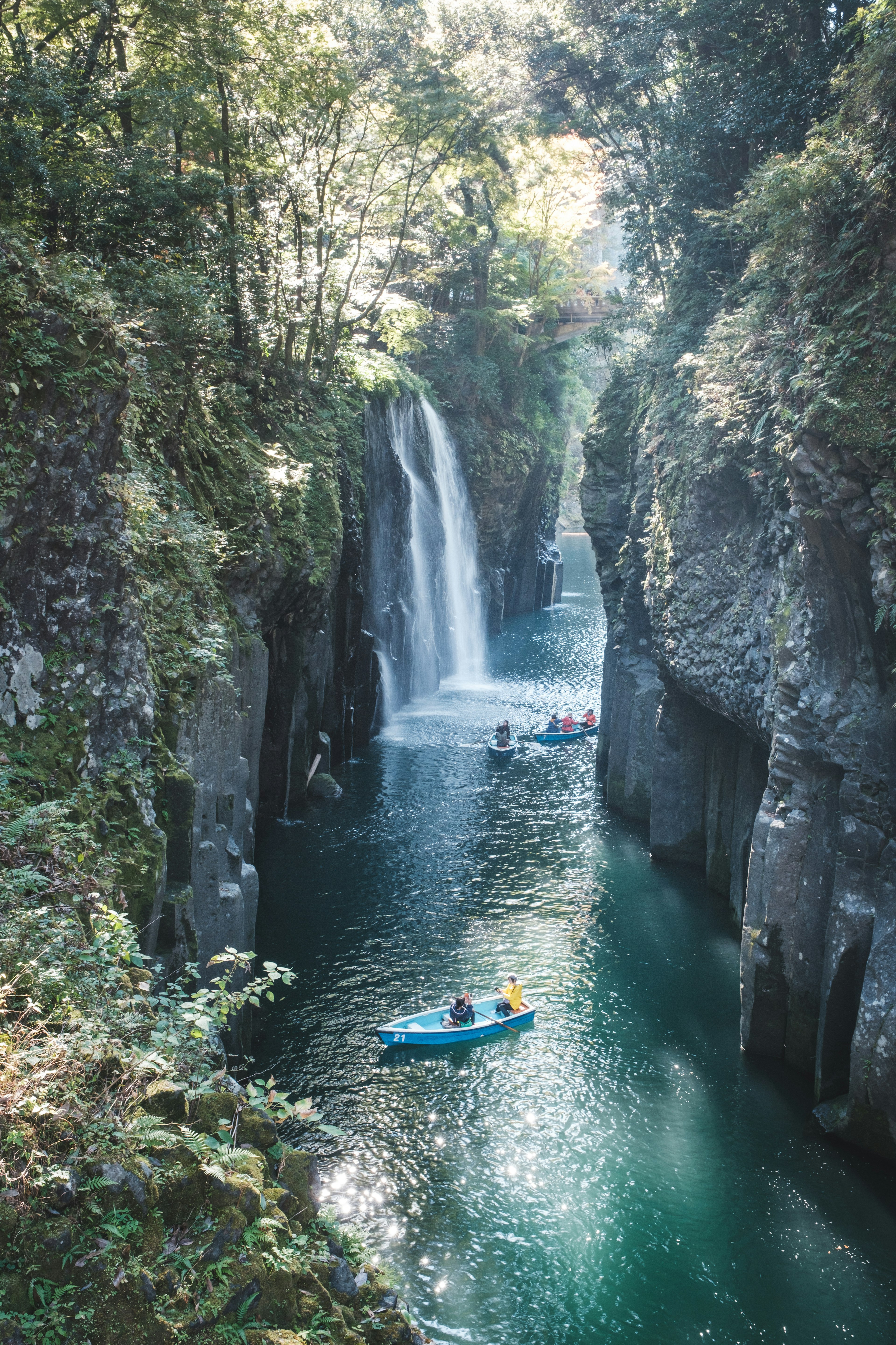 青いカヌーが滝の近くの渓谷を漂う風景緑豊かな植物と清らかな水