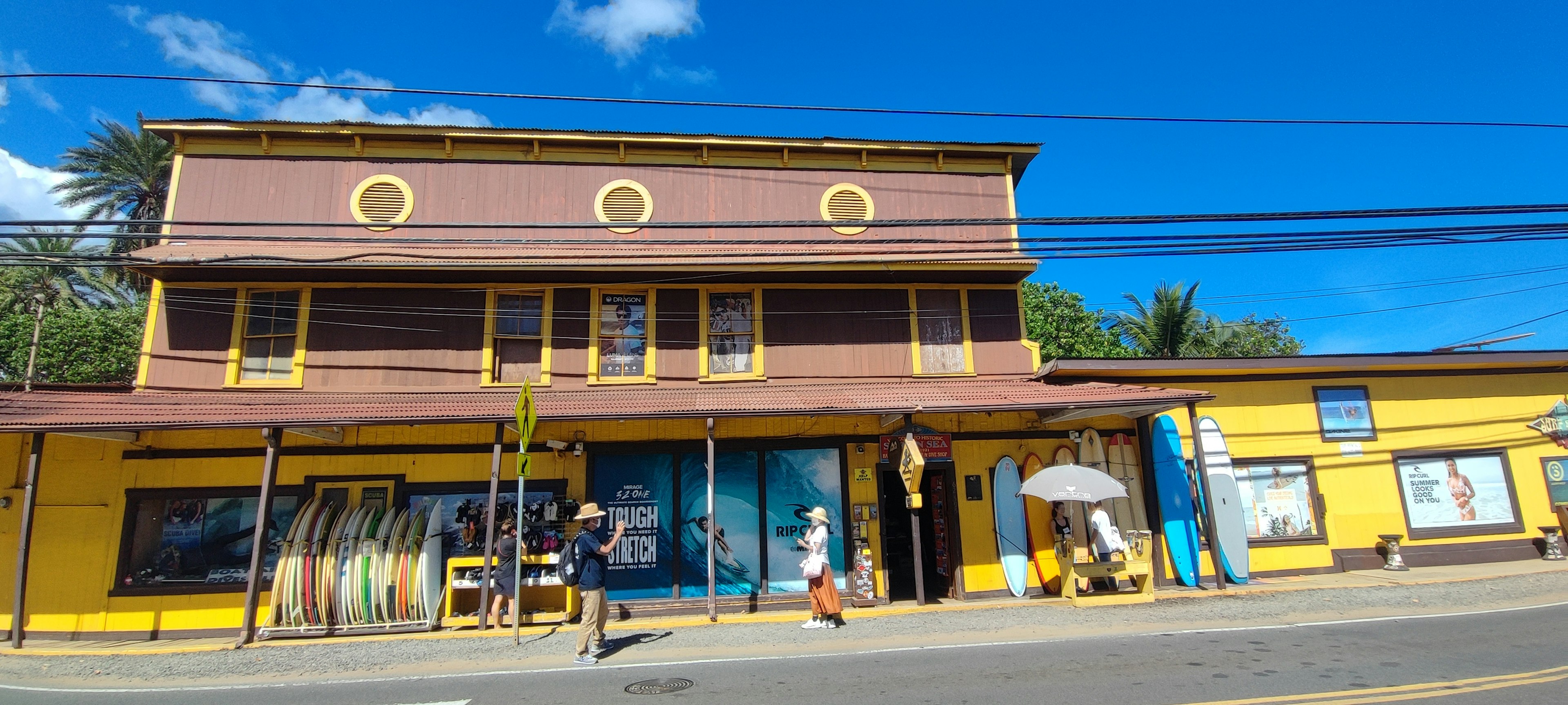 Façade colorée d'un bâtiment avec des personnes marchant sous un ciel bleu