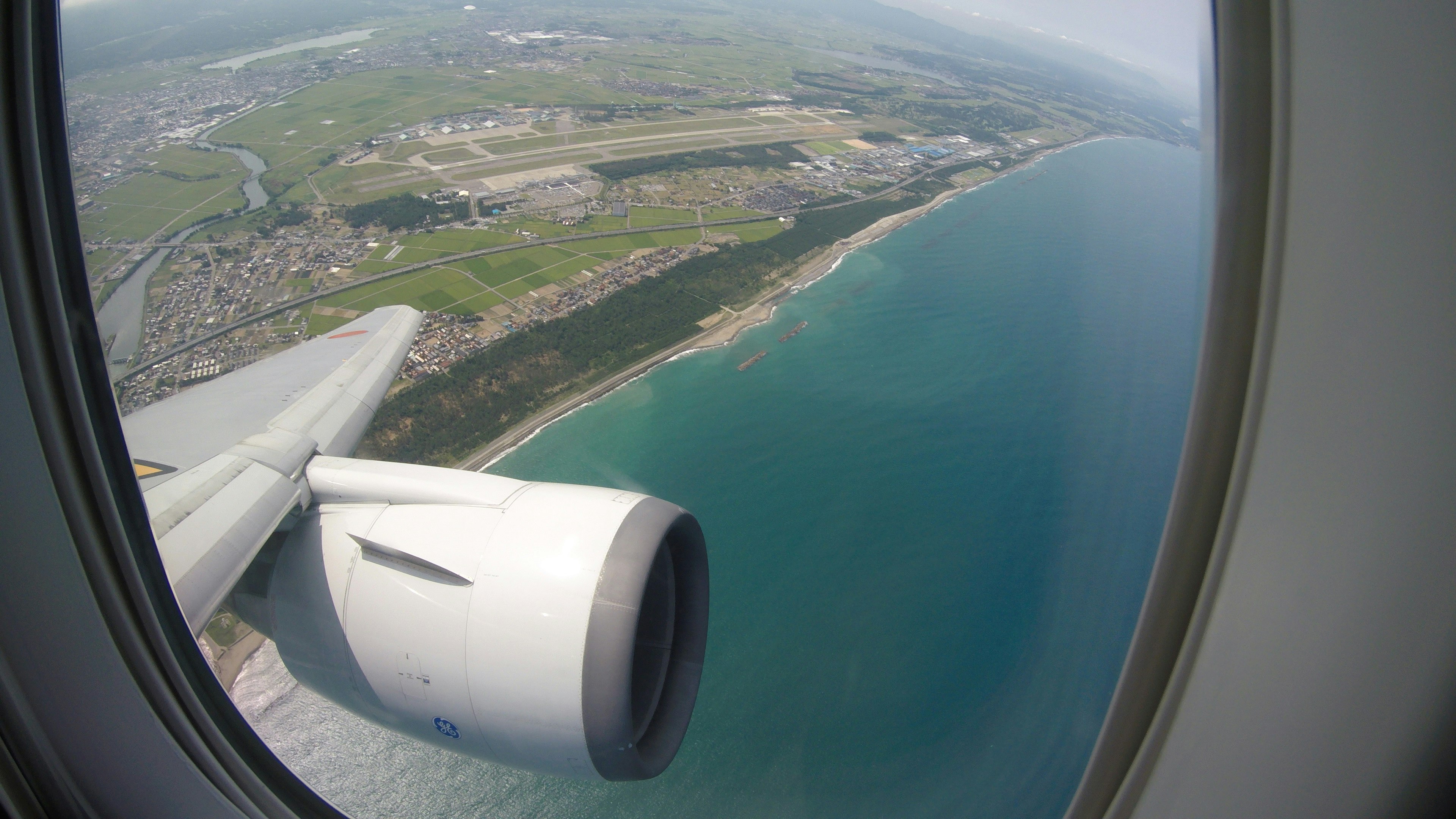 Blick auf die Küste und den Flugzeugmotor vom Fenster