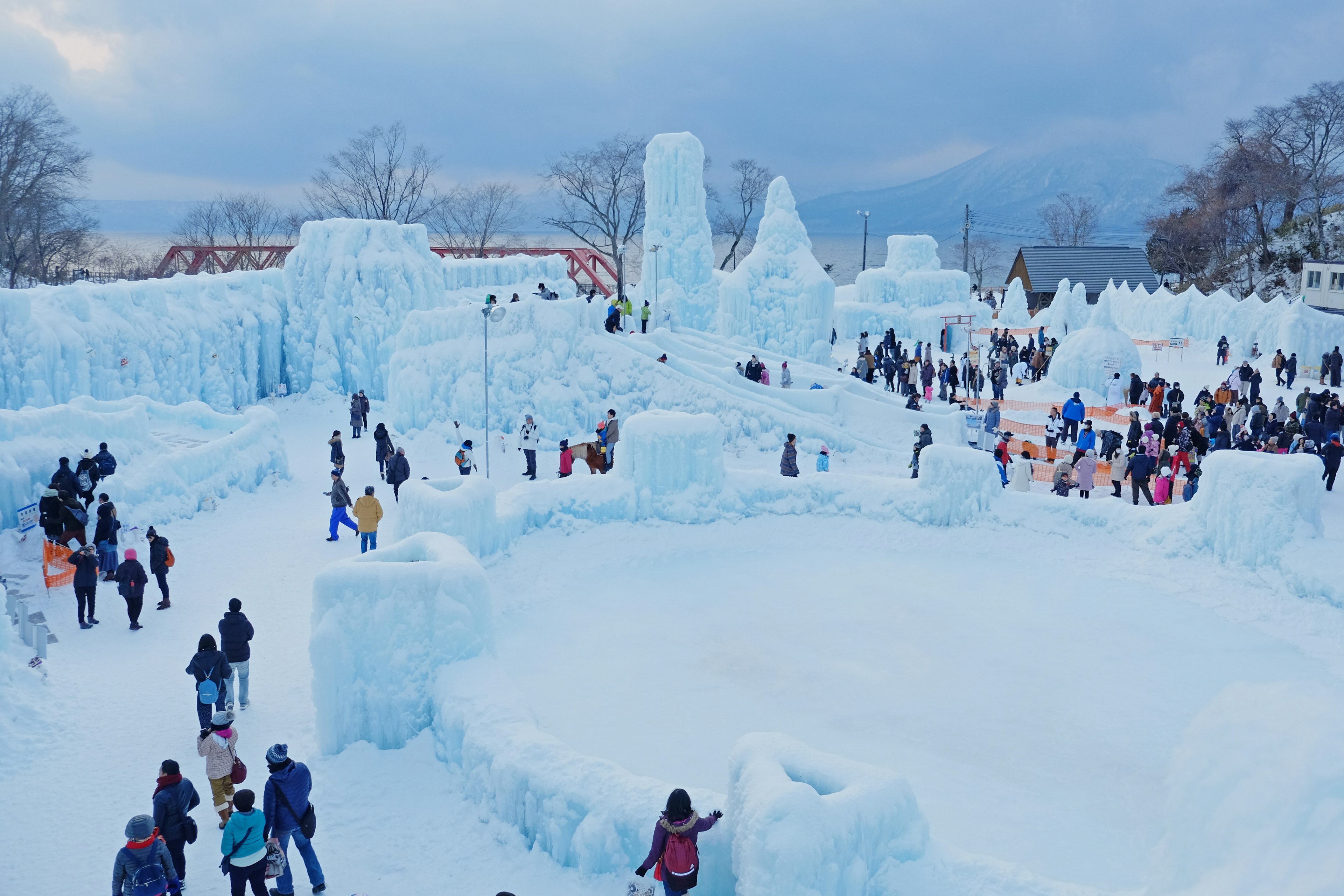 Escena de festival de invierno con esculturas de hielo y estructuras de hielo con muchos visitantes