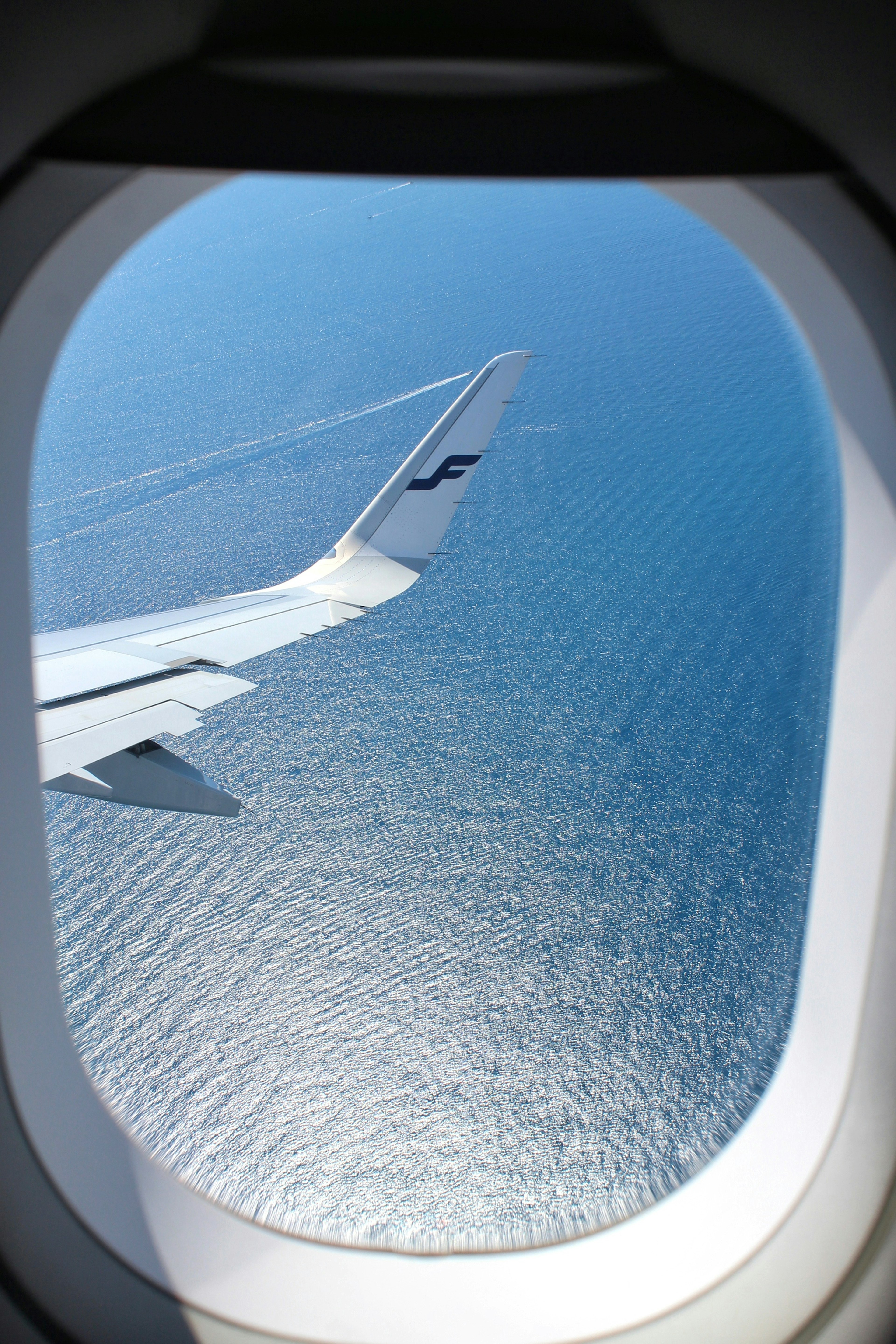 飛行機の窓から見える青い海と翼の一部