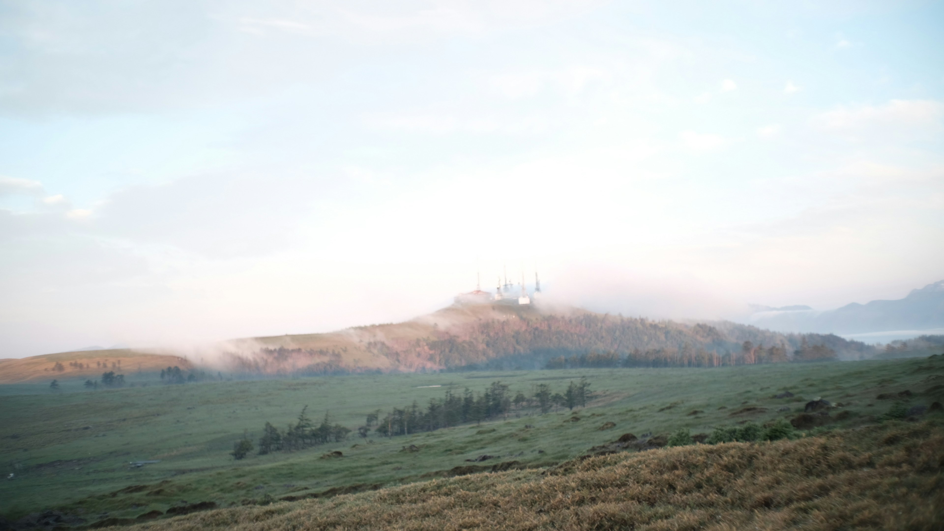 Bukit tertutup kabut dengan langit biru