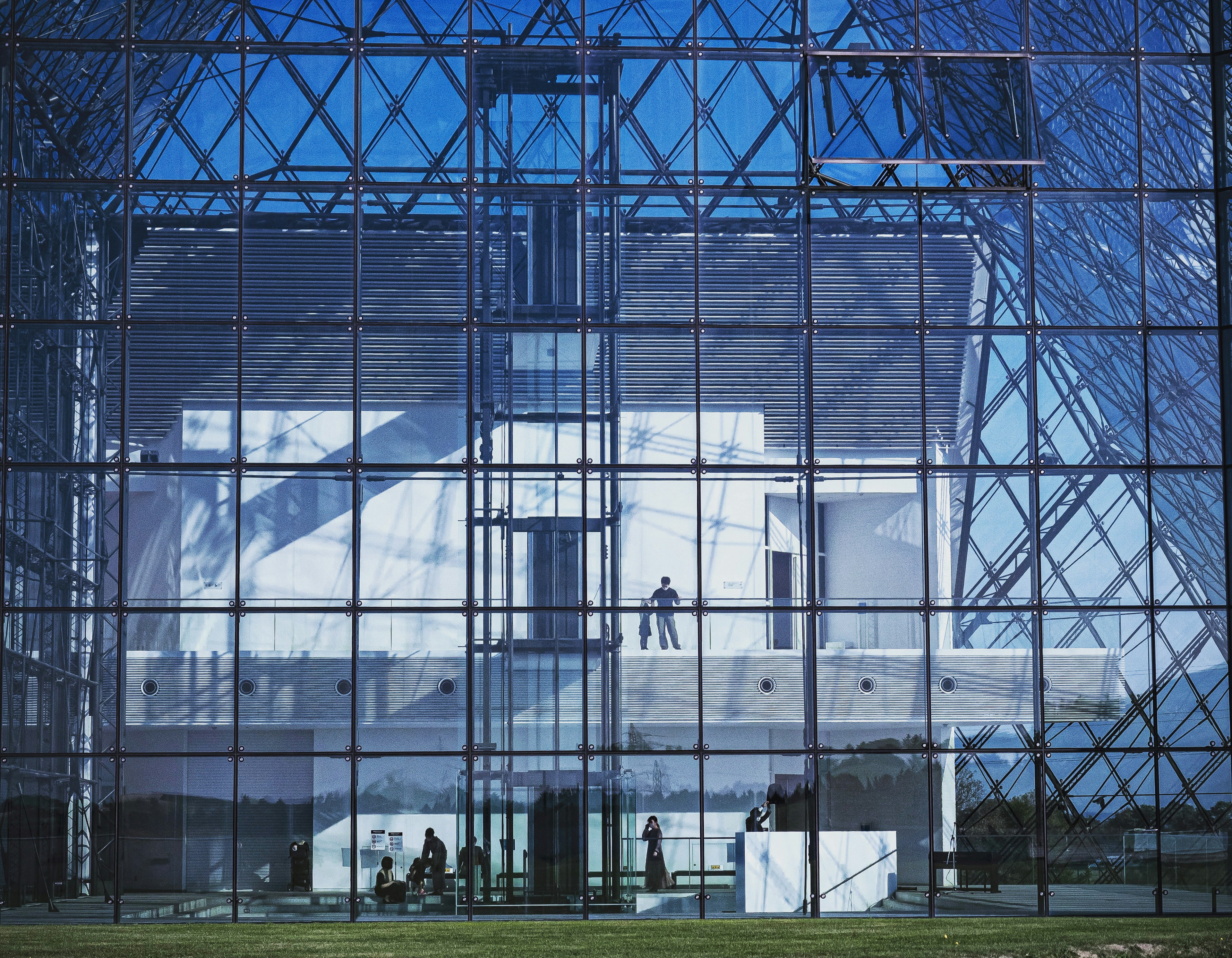 Modern glass building under blue sky featuring people inside