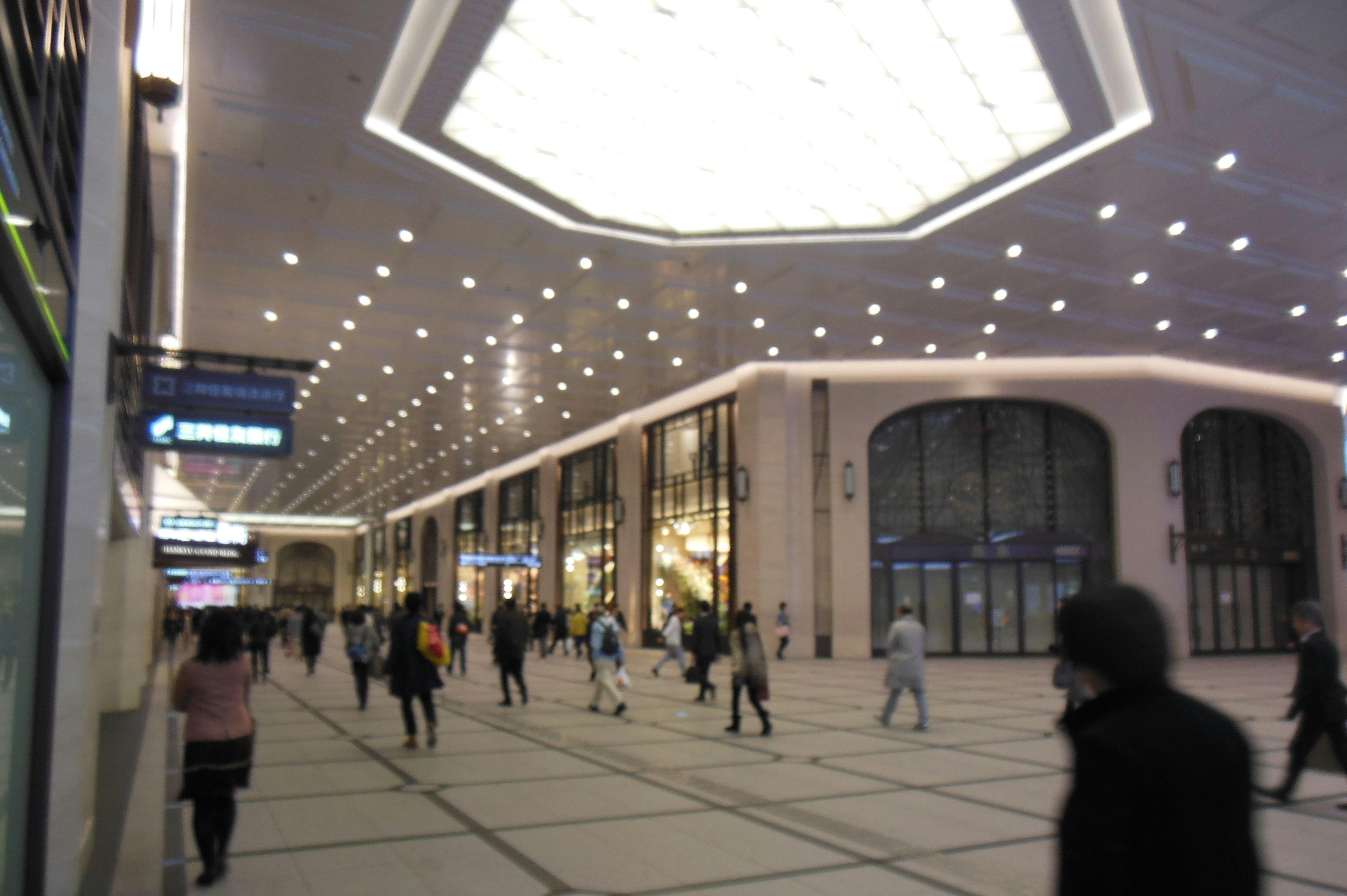 Spacious interior of a station with bright lighting and many people walking