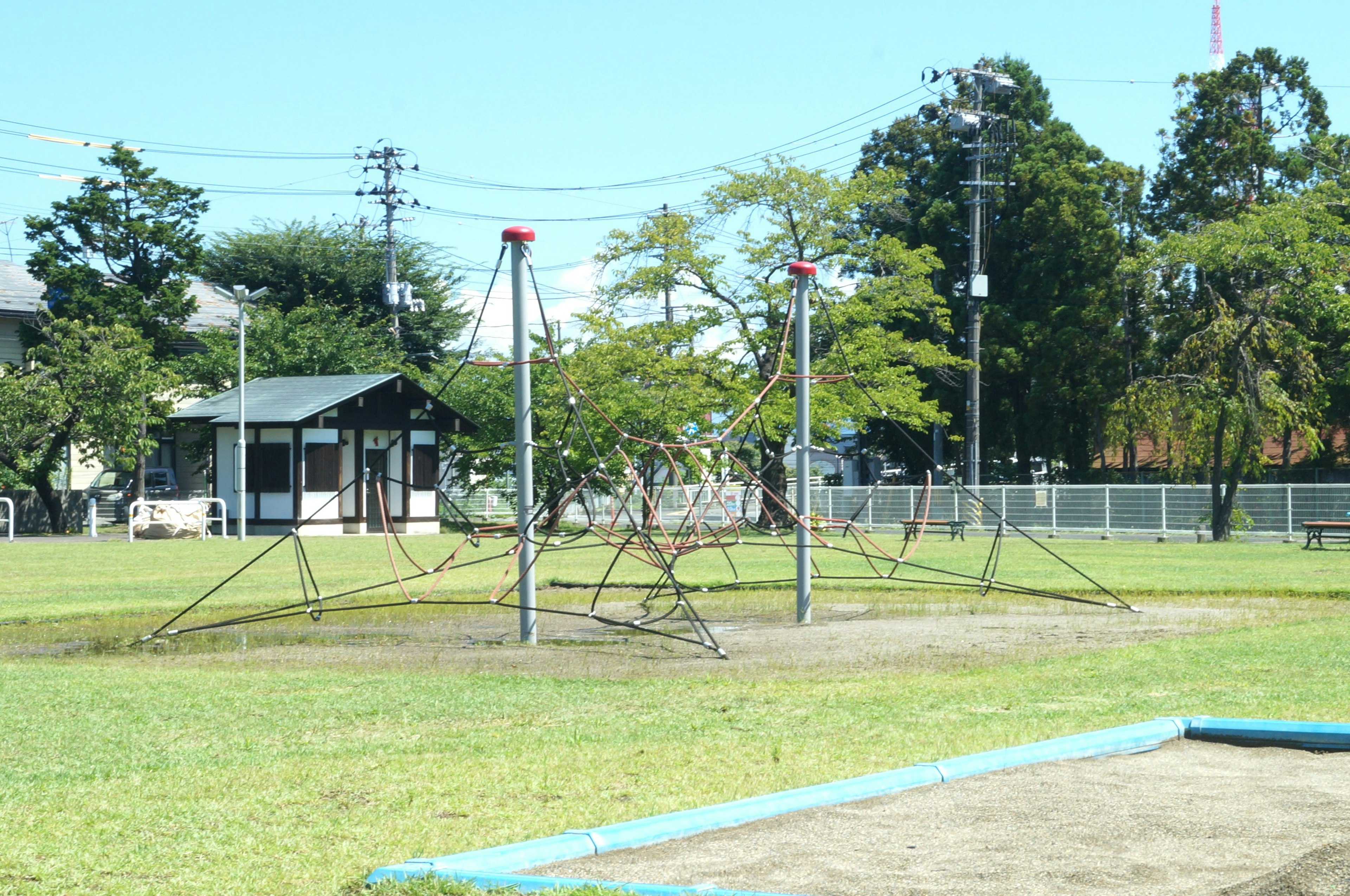 Peralatan taman bermain dengan rumput hijau di sekitarnya