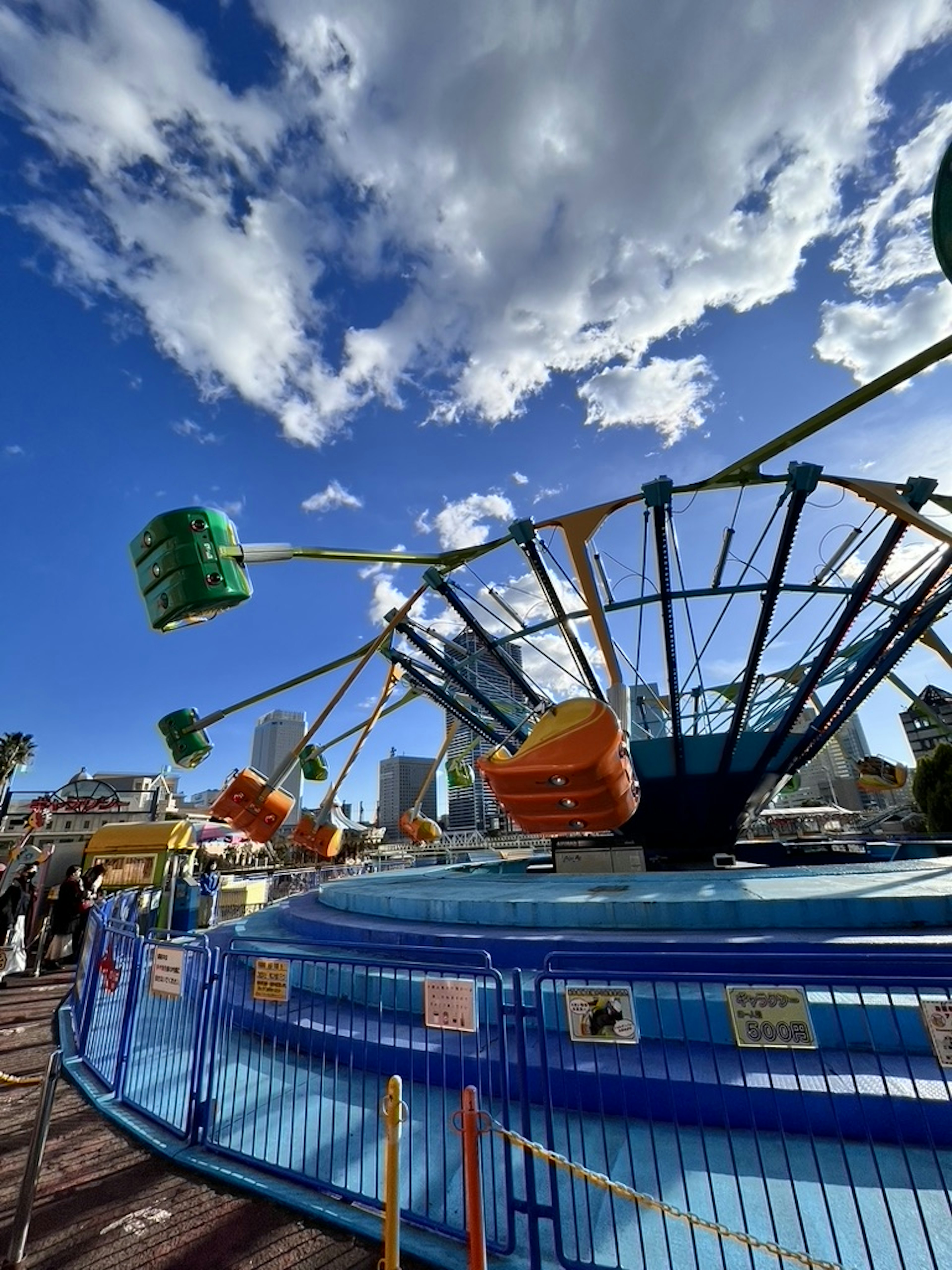 Atracción colorida de parque de diversiones con base azul y cielo nublado