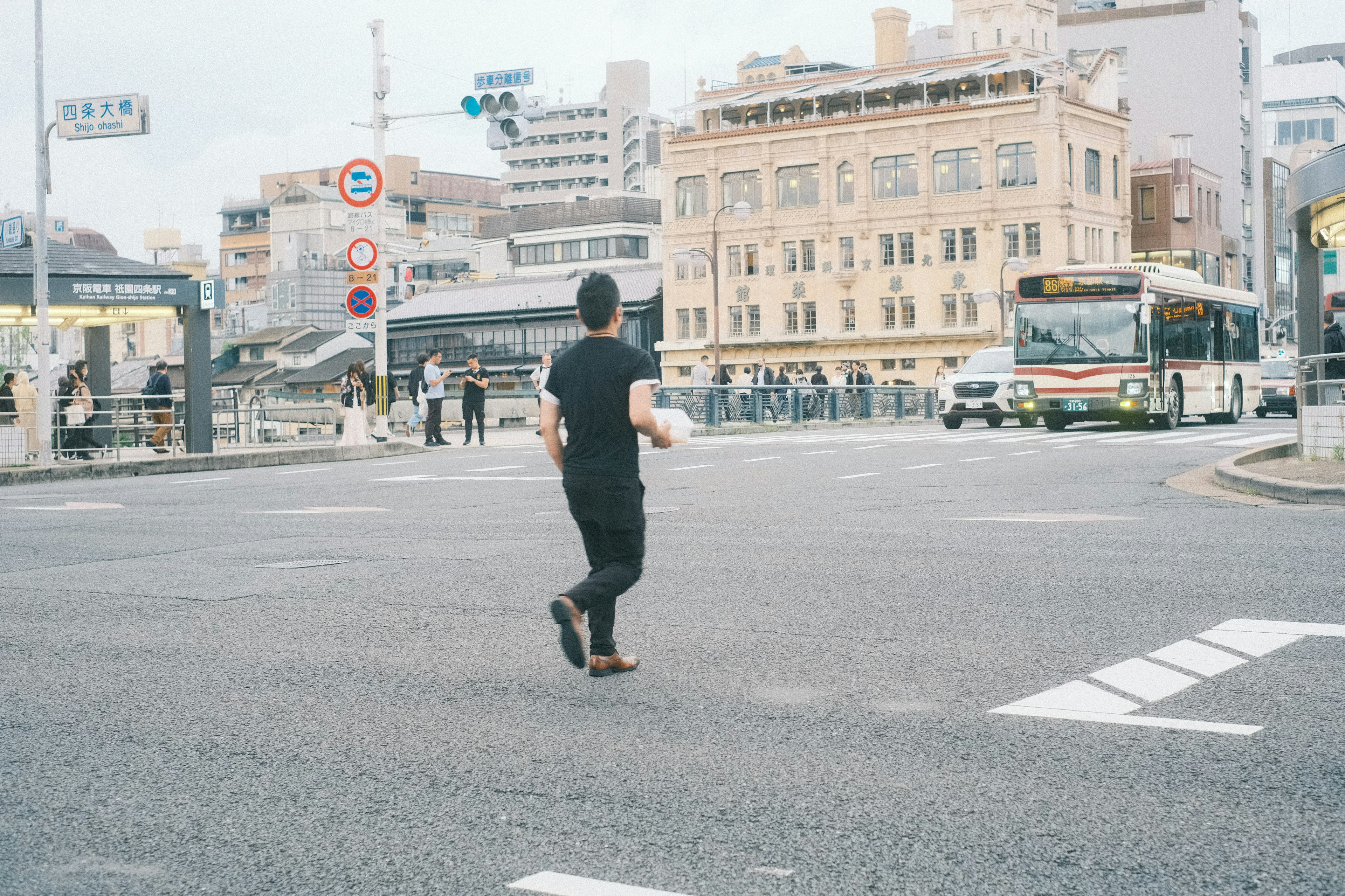 黒い服を着た男性が交差点を渡る風景