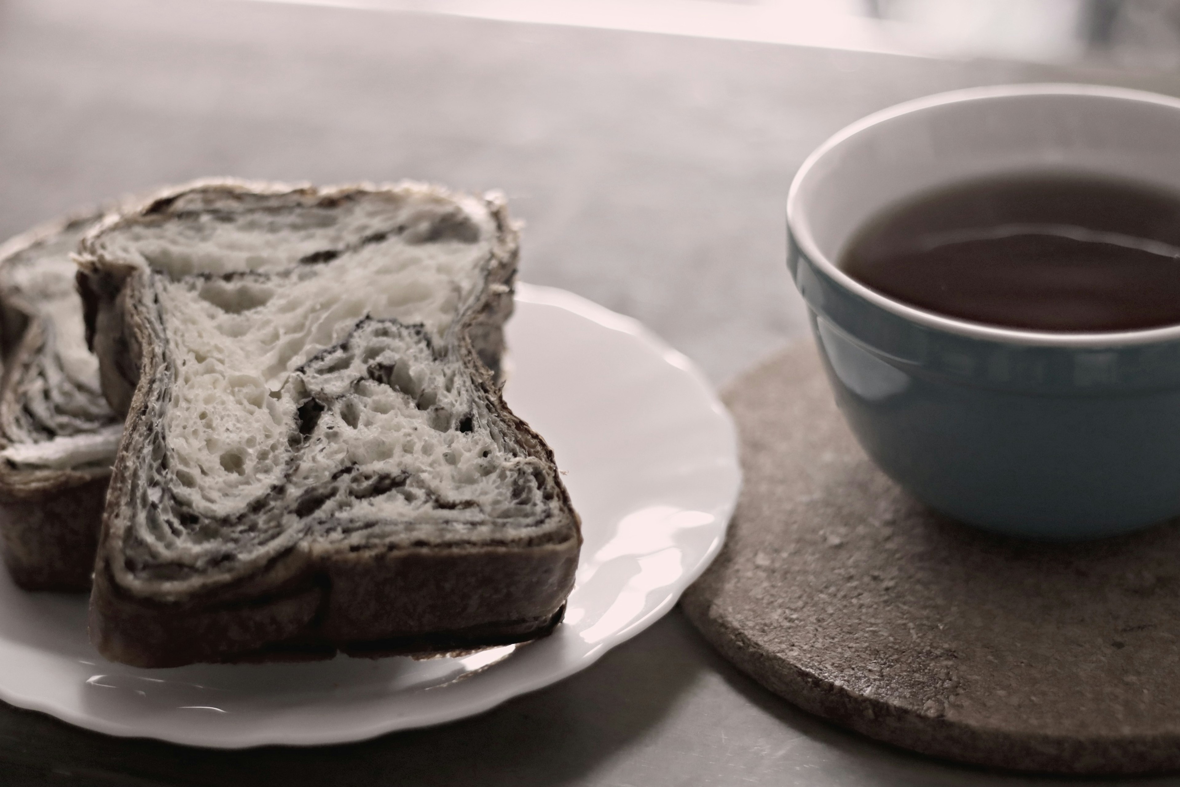 Sliced marble bread next to a blue tea cup on a table