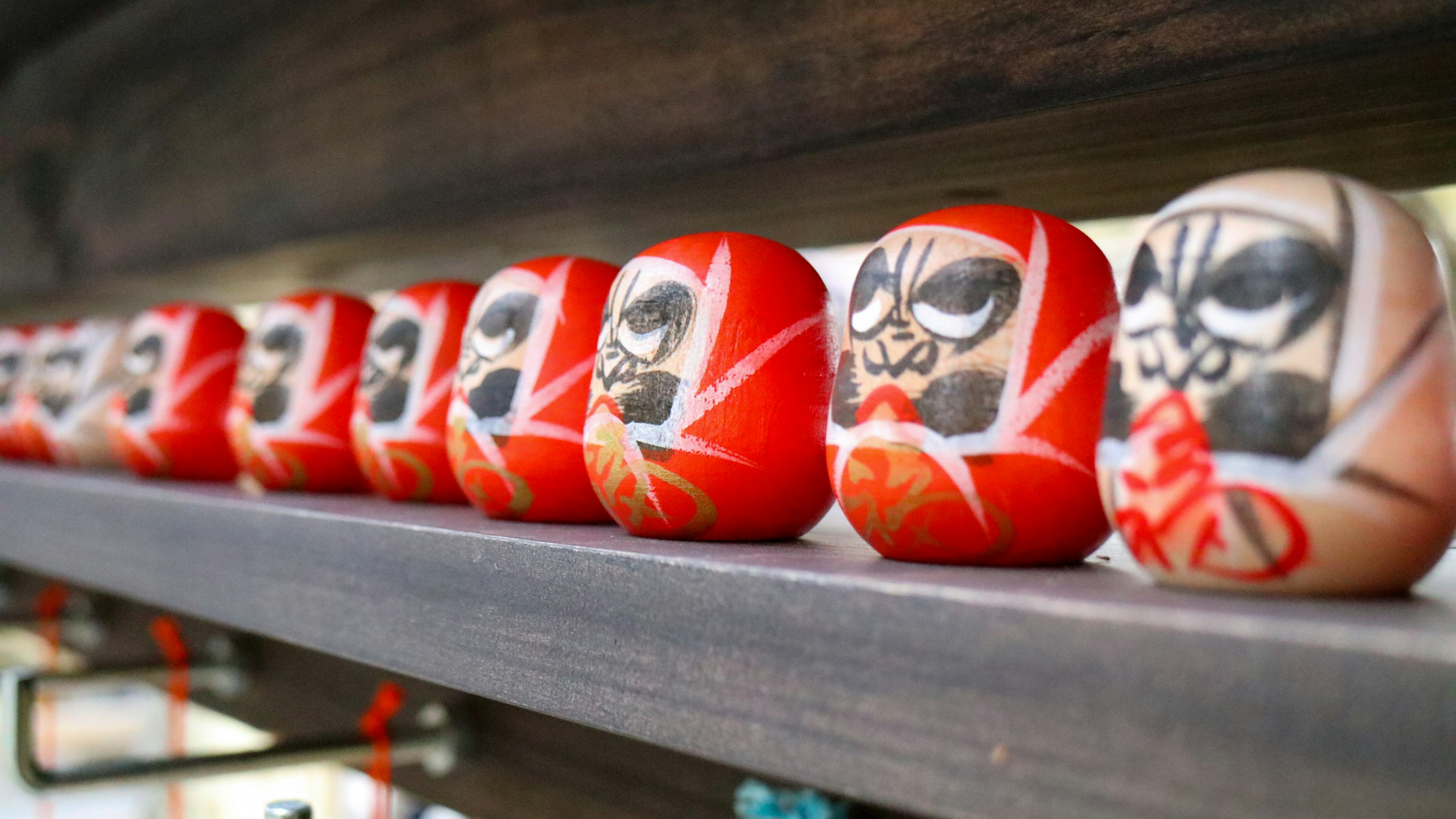 A row of red Daruma dolls with distinct facial features