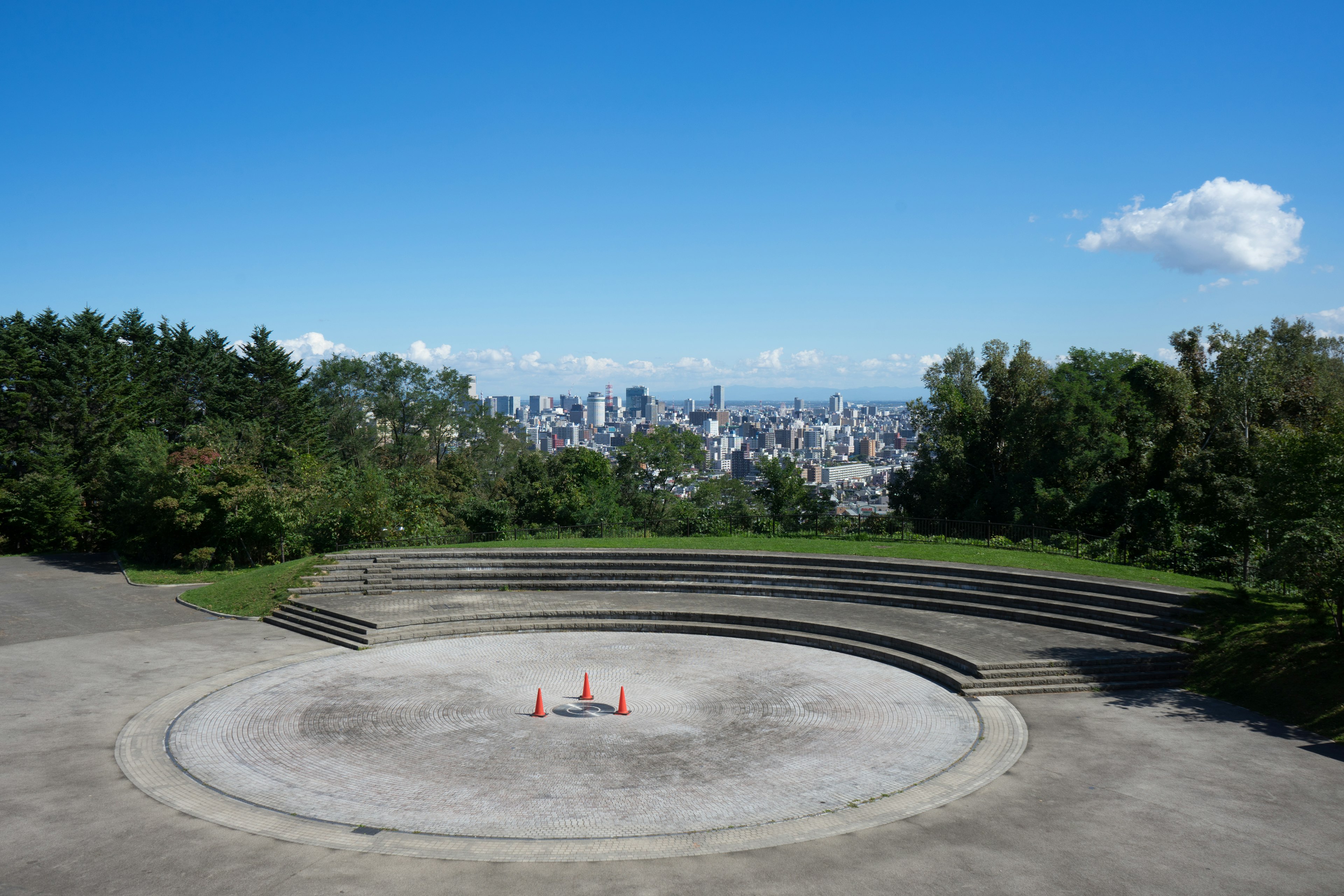 Scène circulaire avec skyline de la ville en arrière-plan sous un ciel bleu clair