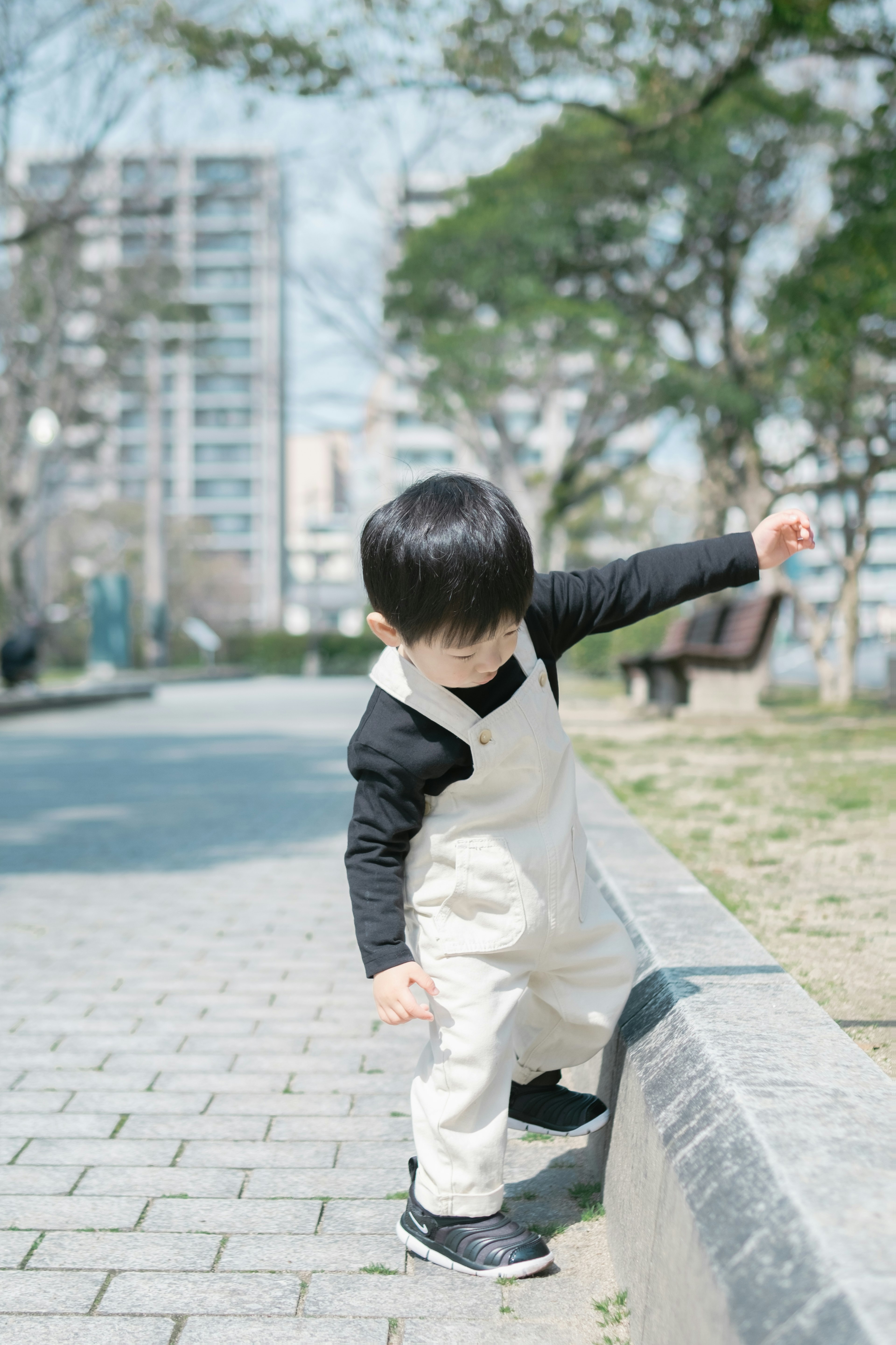 公園で遊ぶ子供が白いオーバーオールを着ている