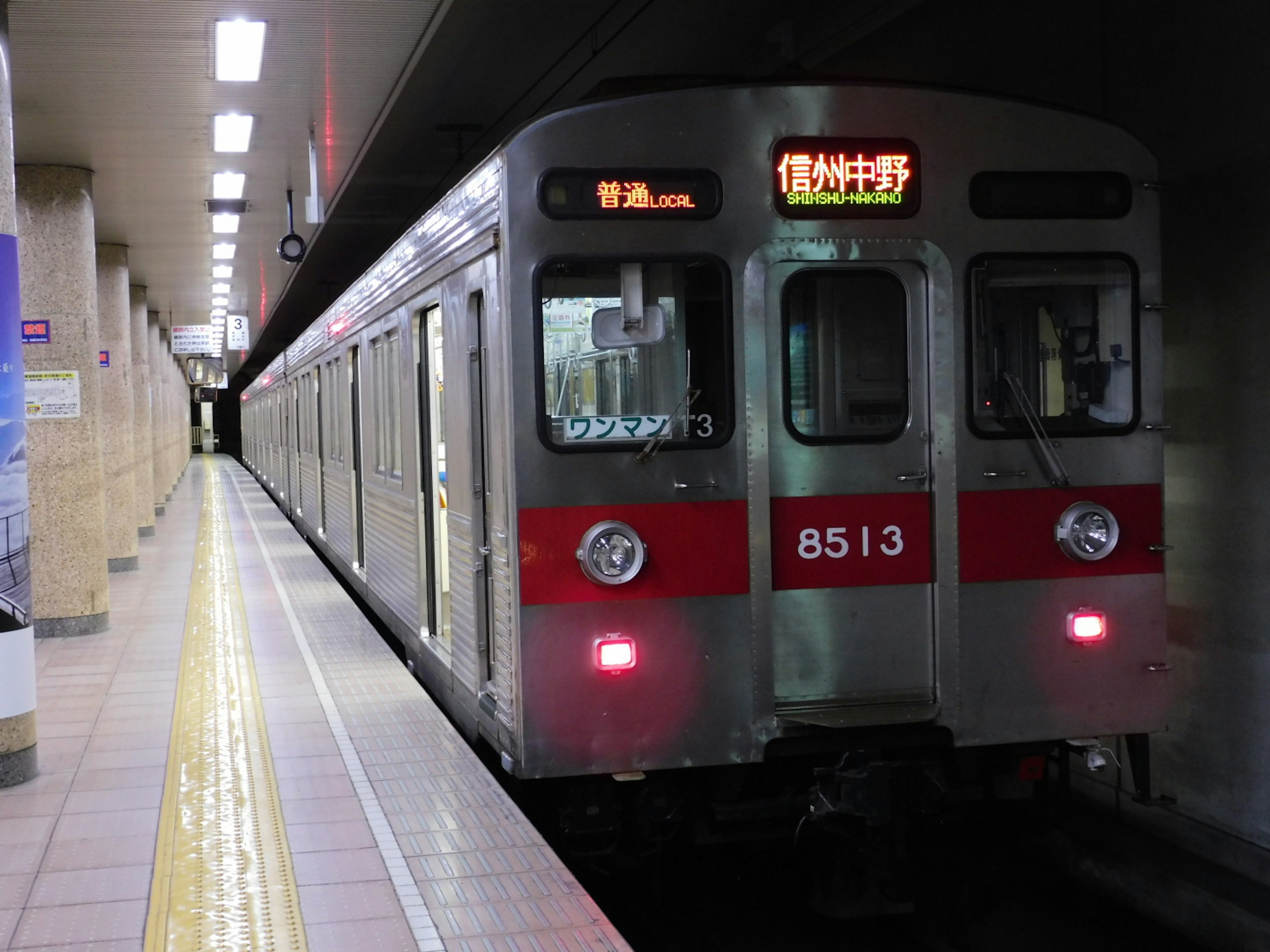 Silver subway train with red stripes stopped at the station