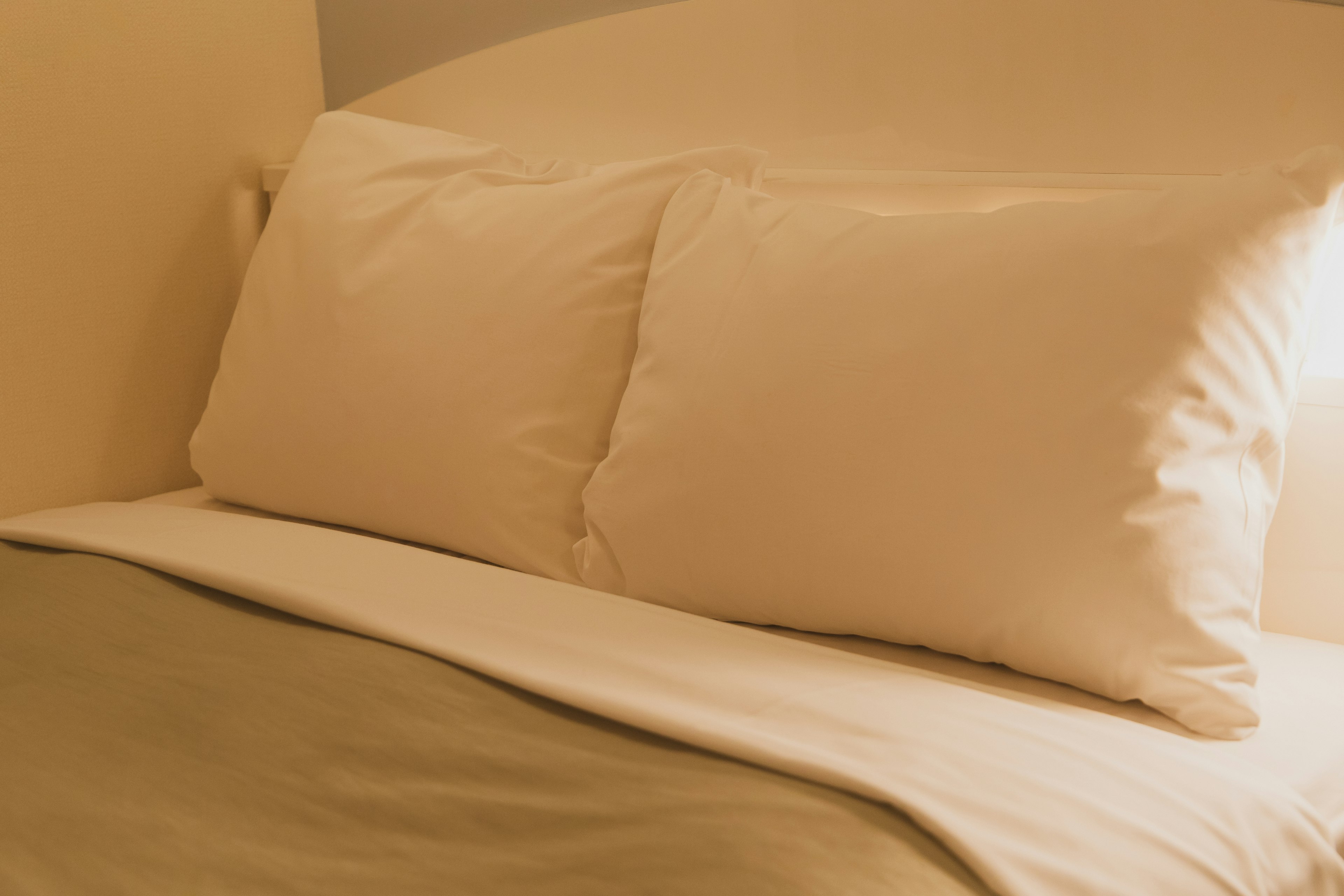 Cream-colored pillows on a bed with light green sheets