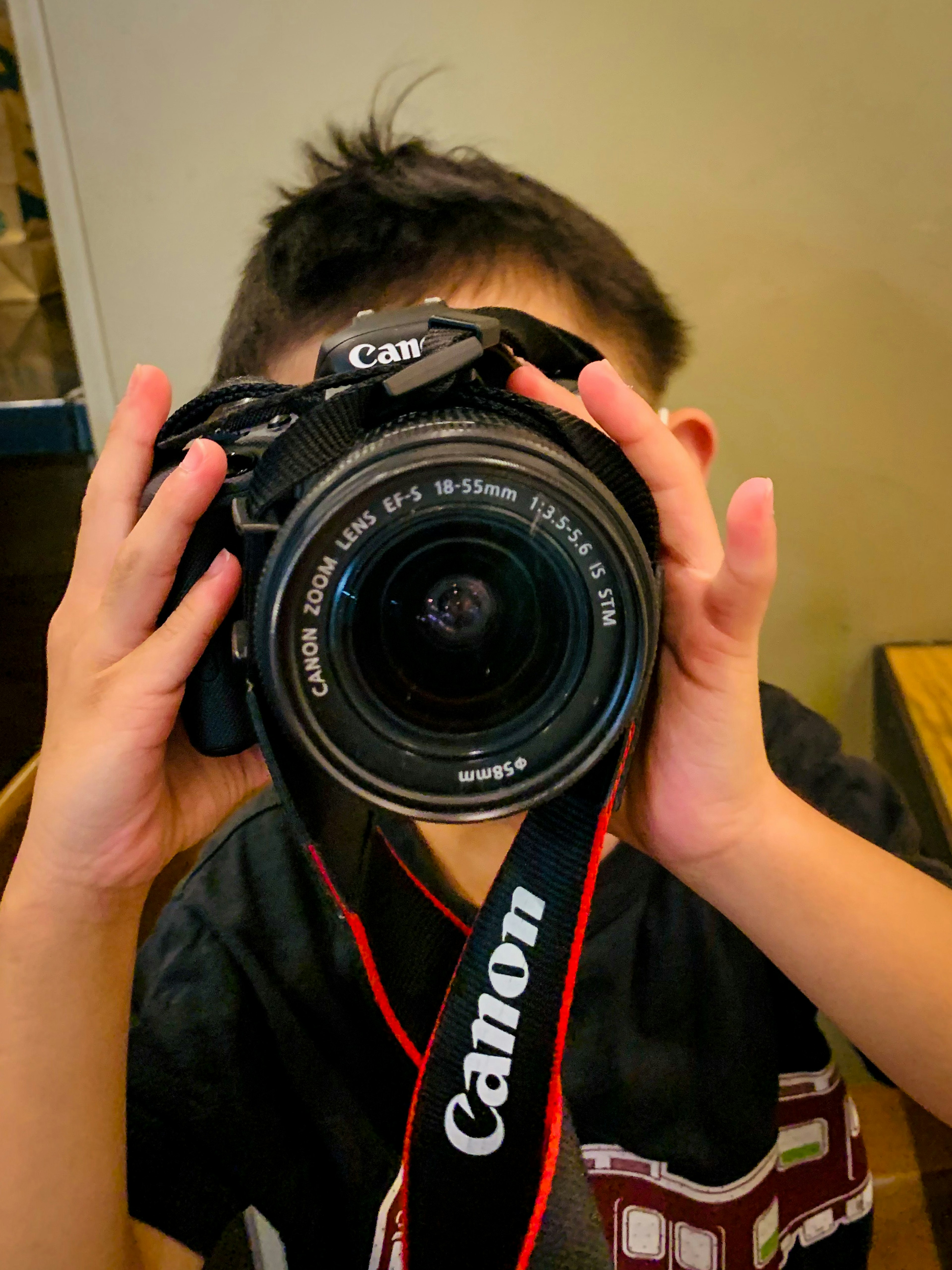 A child holding a Canon camera with a visible lens