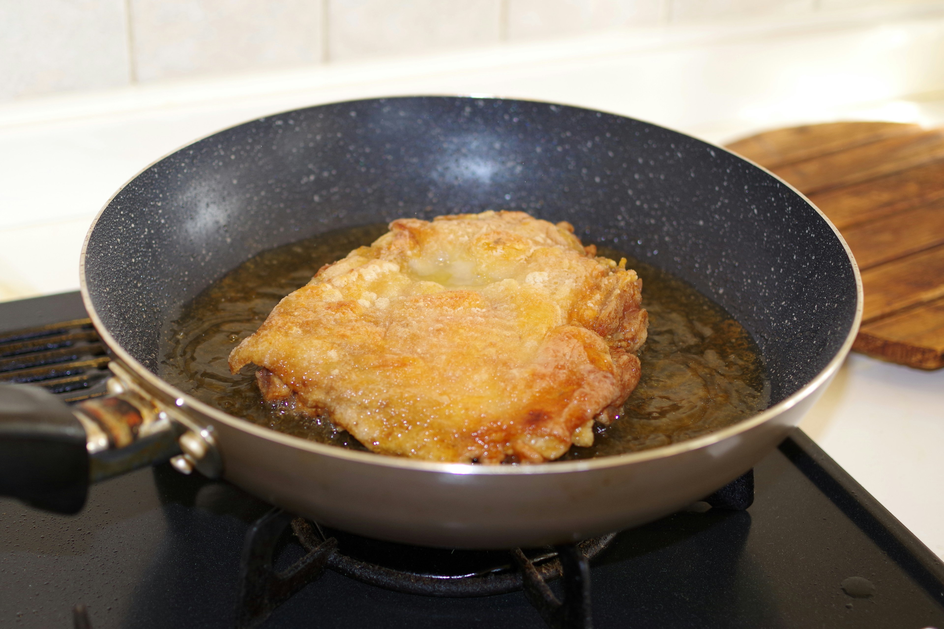 Fillet dada ayam besar yang sedang digoreng di wajan