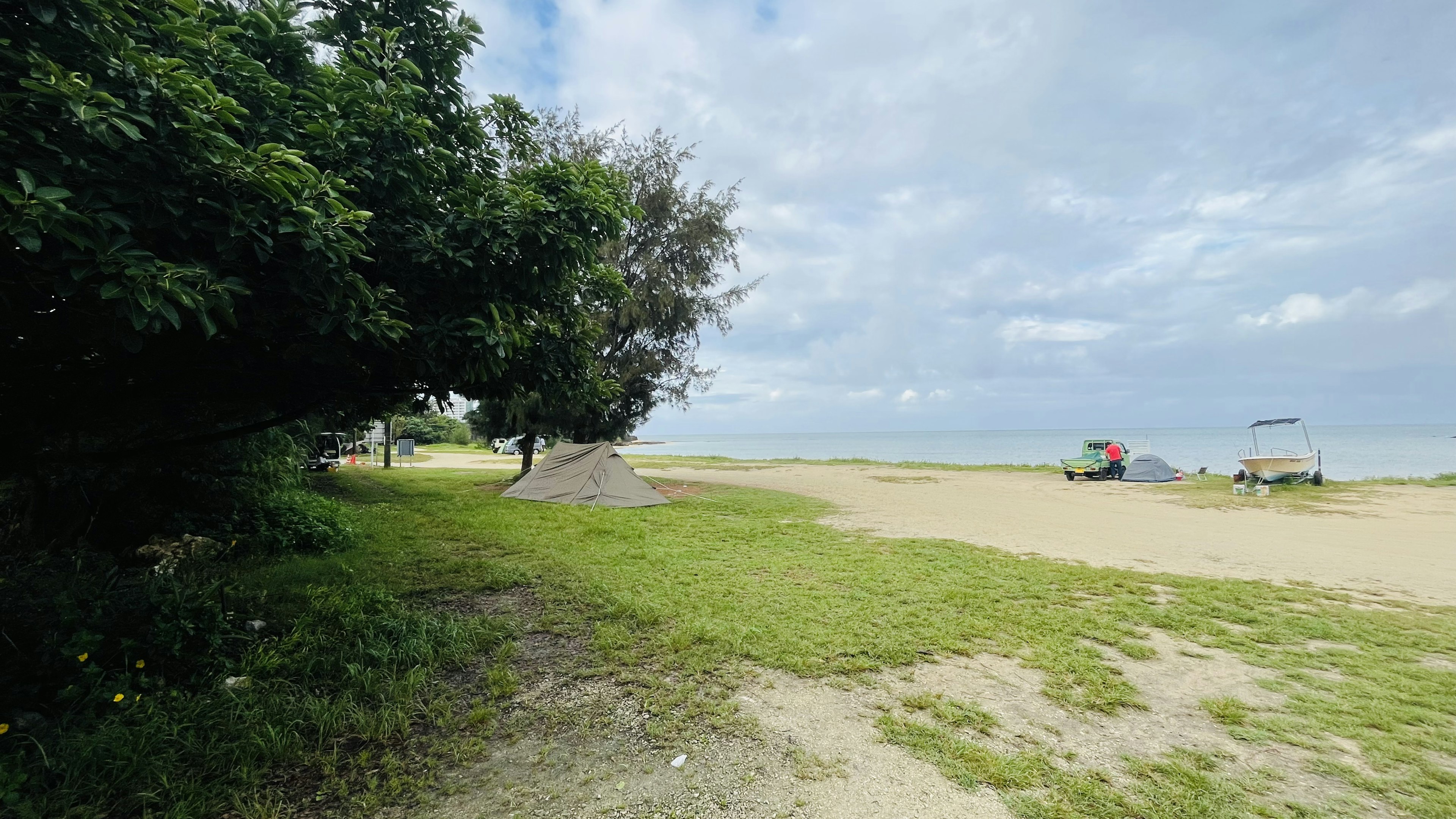 Une zone de plage verte entourée de mer et de ciel avec des nuages épars