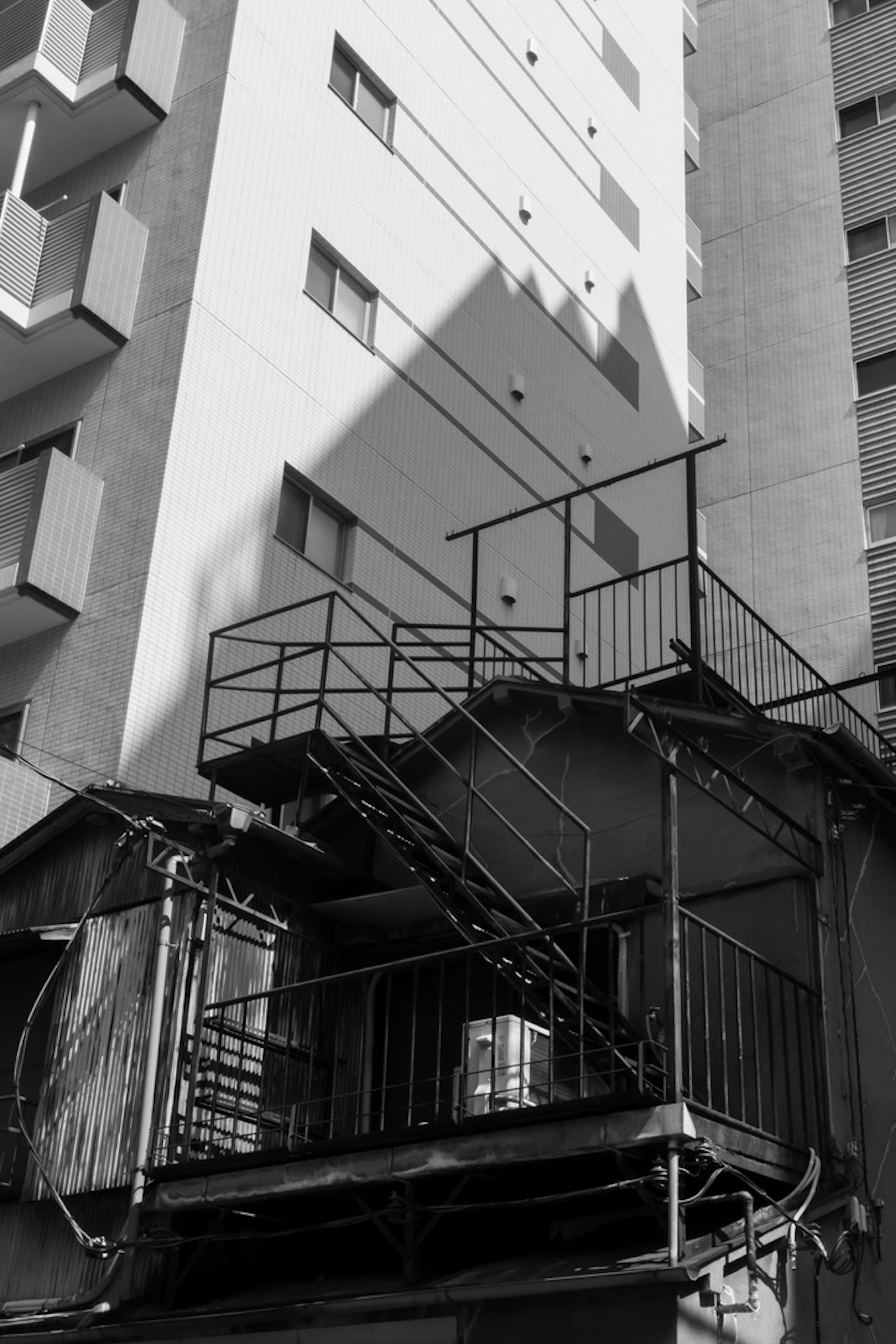 Scène urbaine avec un escalier et des ombres marquantes sur un bâtiment