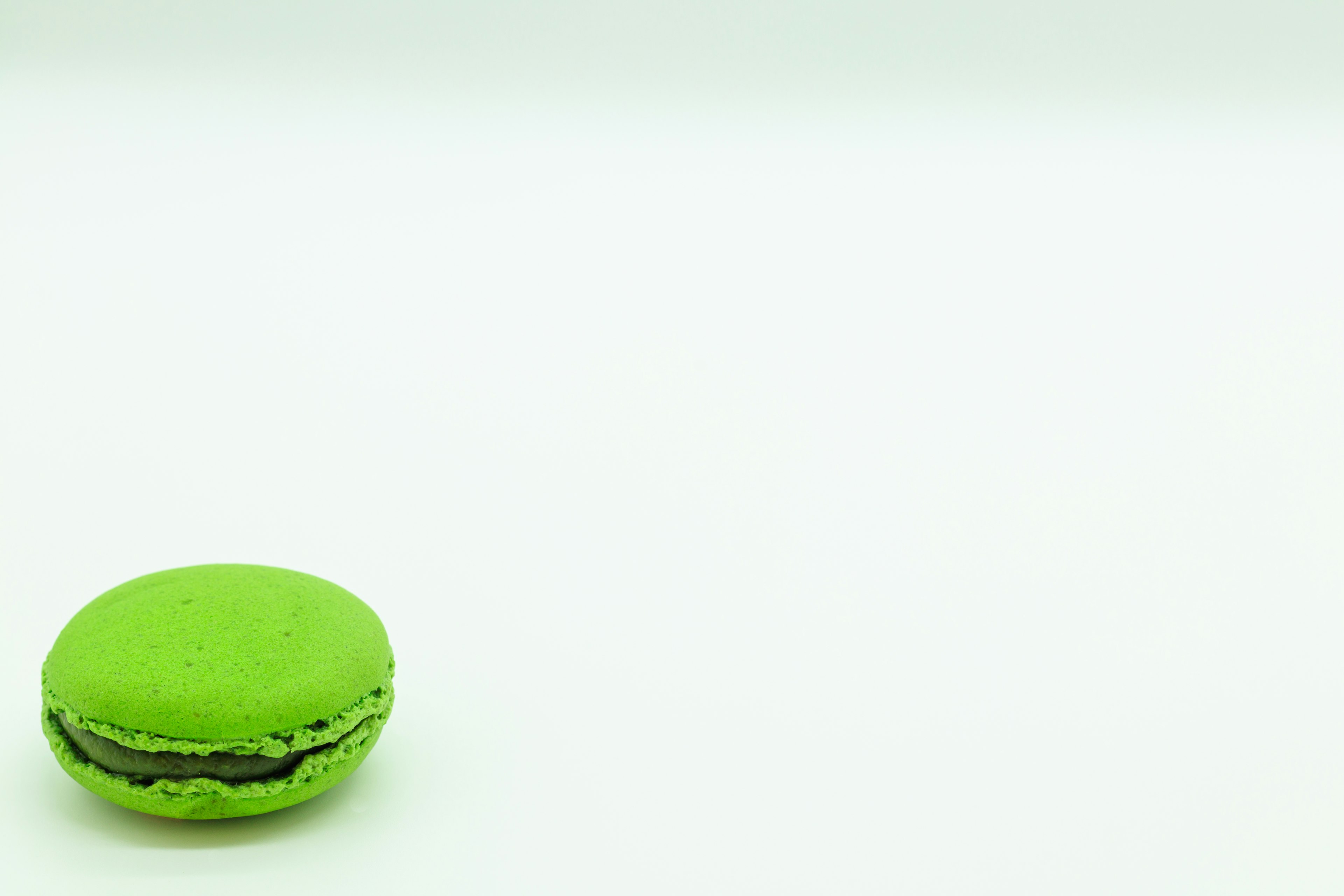 Ein lebendiger grüner Macaron auf einem weißen Hintergrund