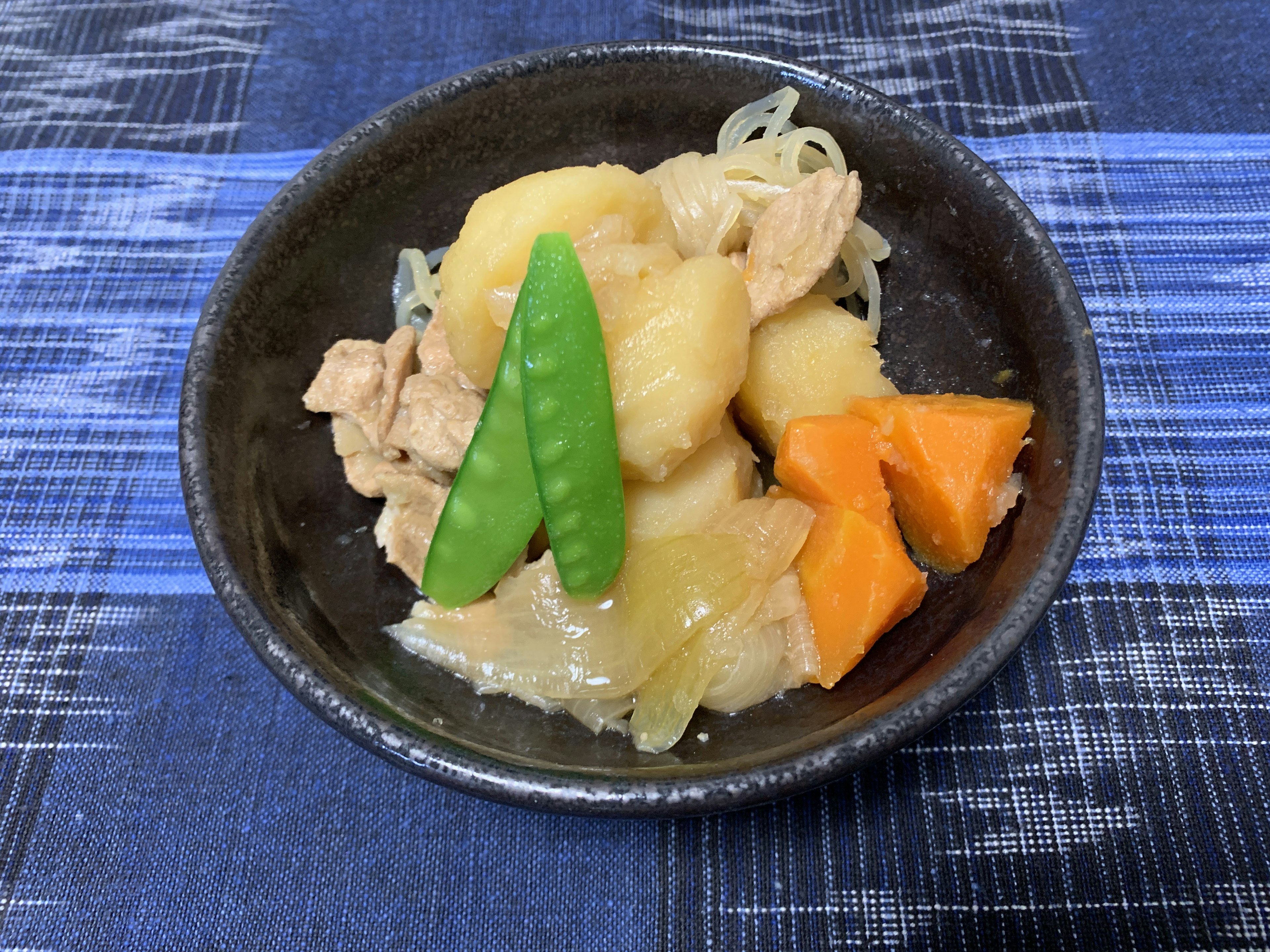 鶏肉と野菜の煮物が盛り付けられた黒い器