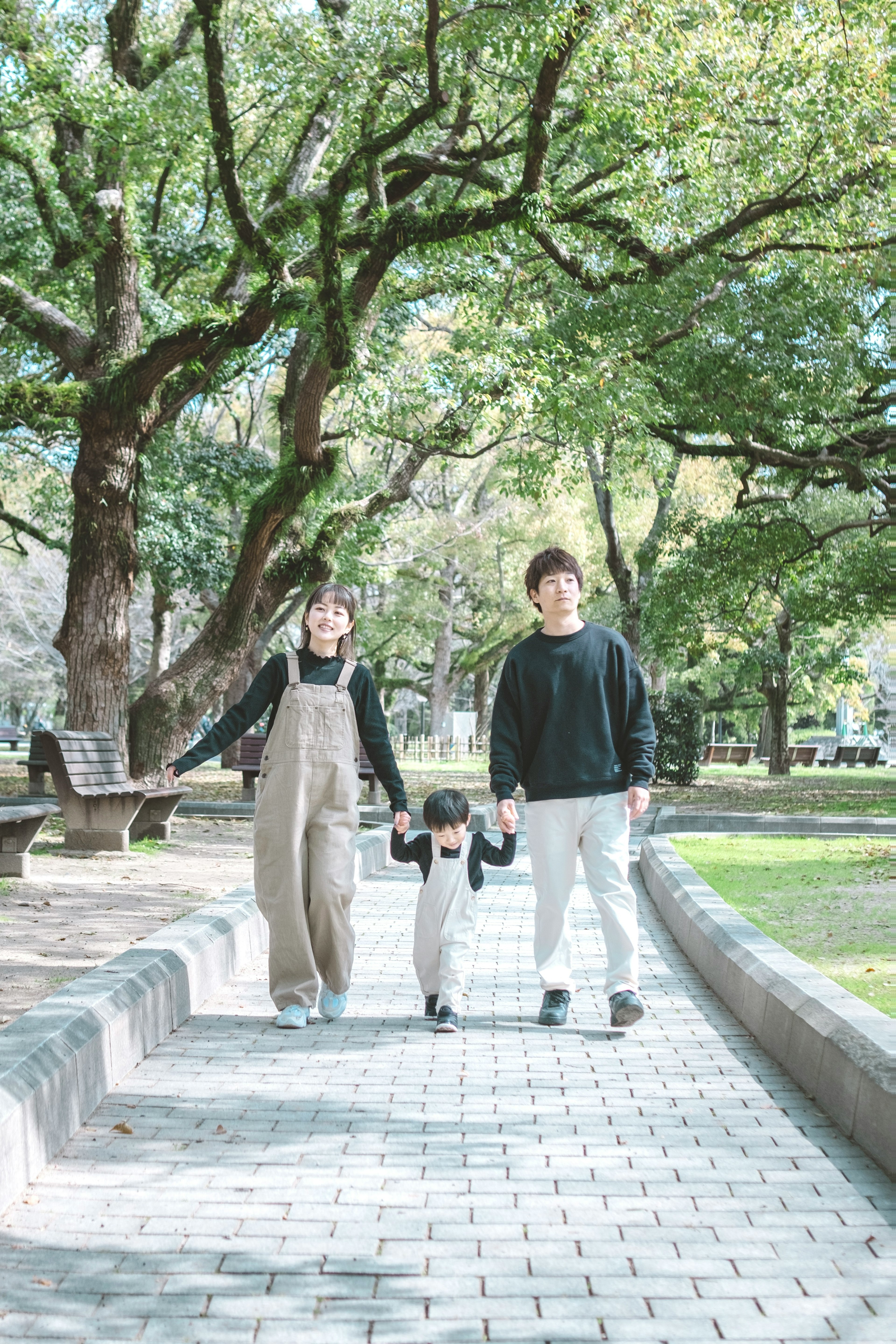 家族が公園の小道を散歩している緑の木々に囲まれた風景