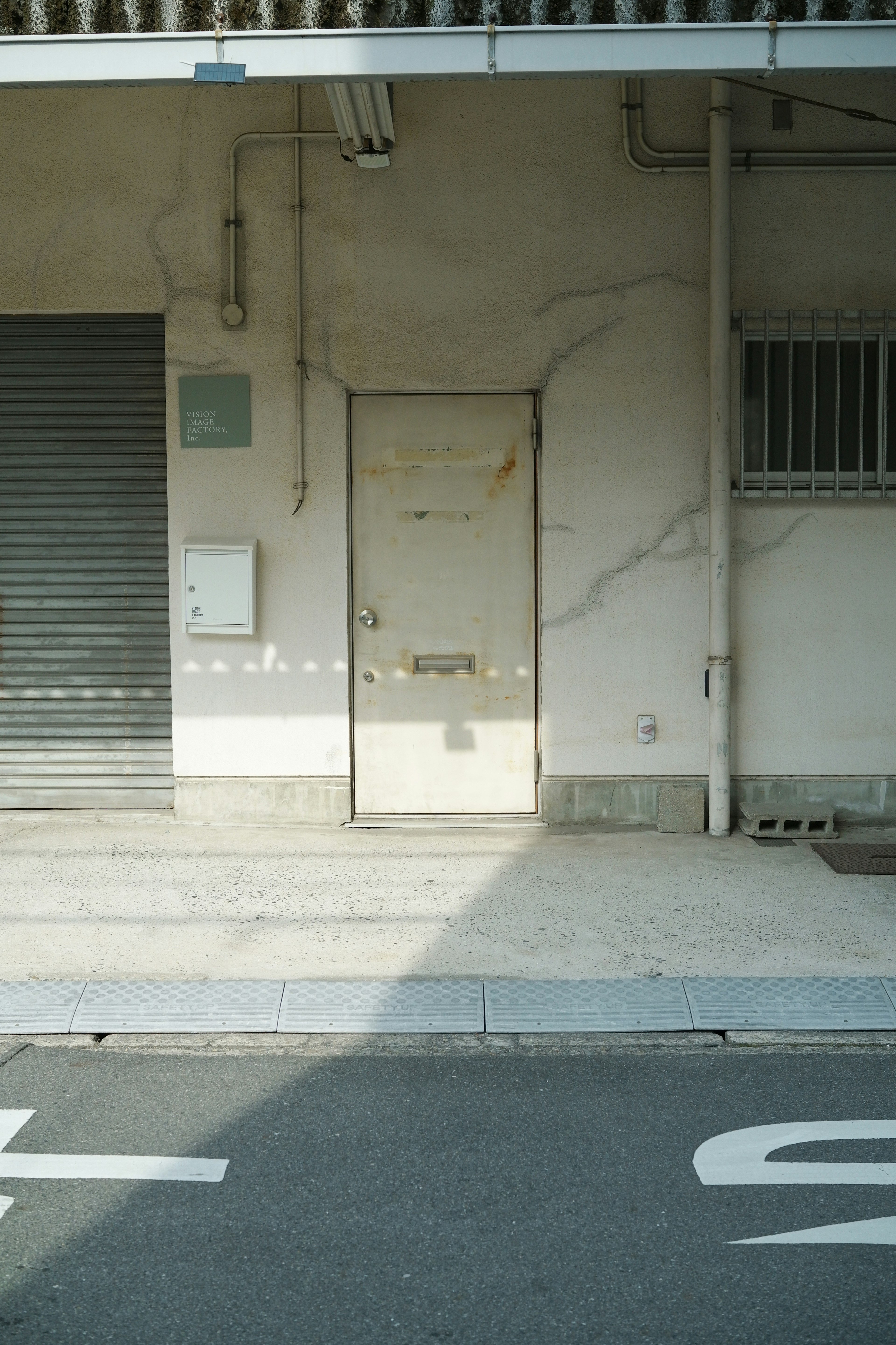 Scena urbana con una vecchia porta e una serranda su un muro bianco