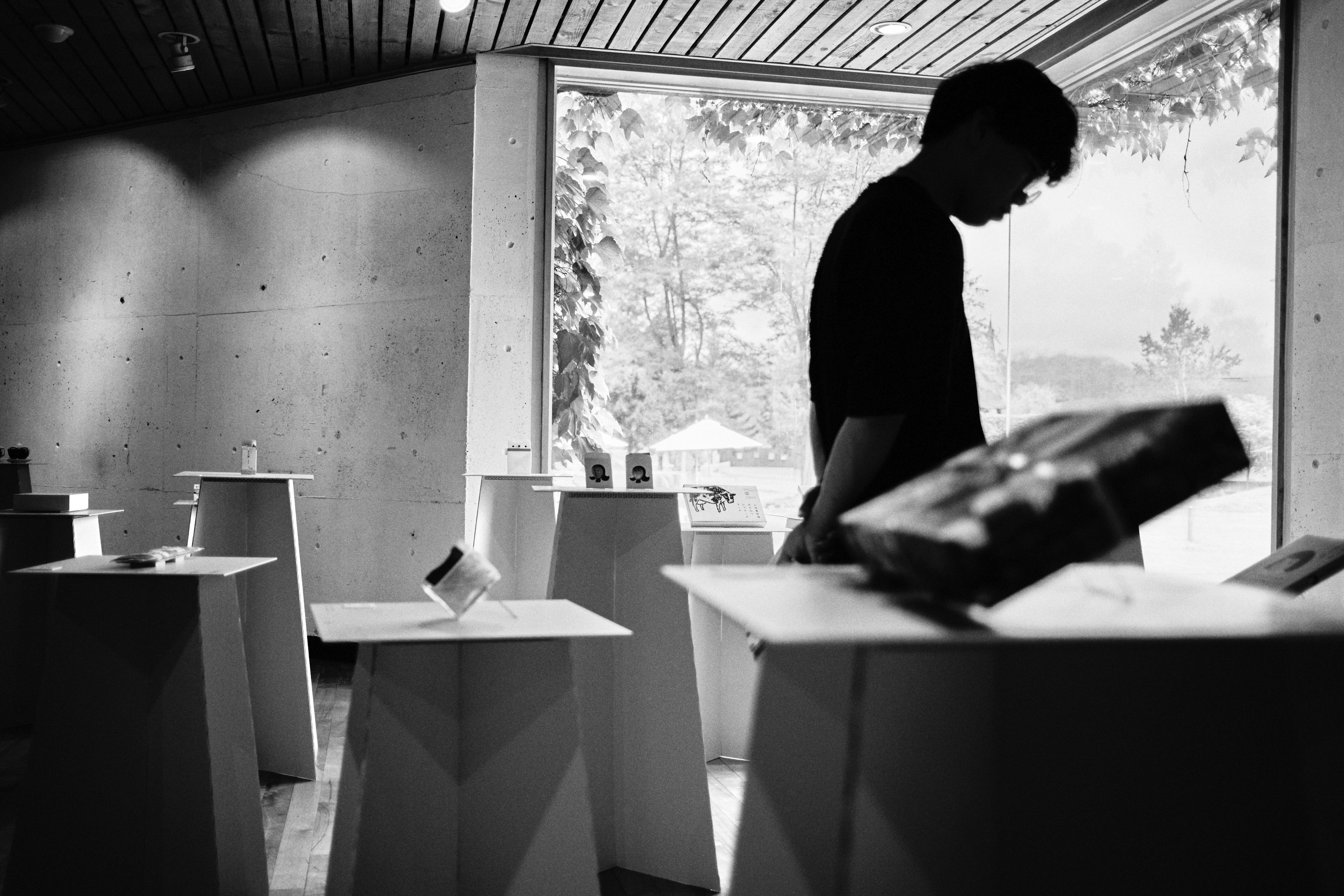 Silhouette of a person observing objects in a display space with a black and white background