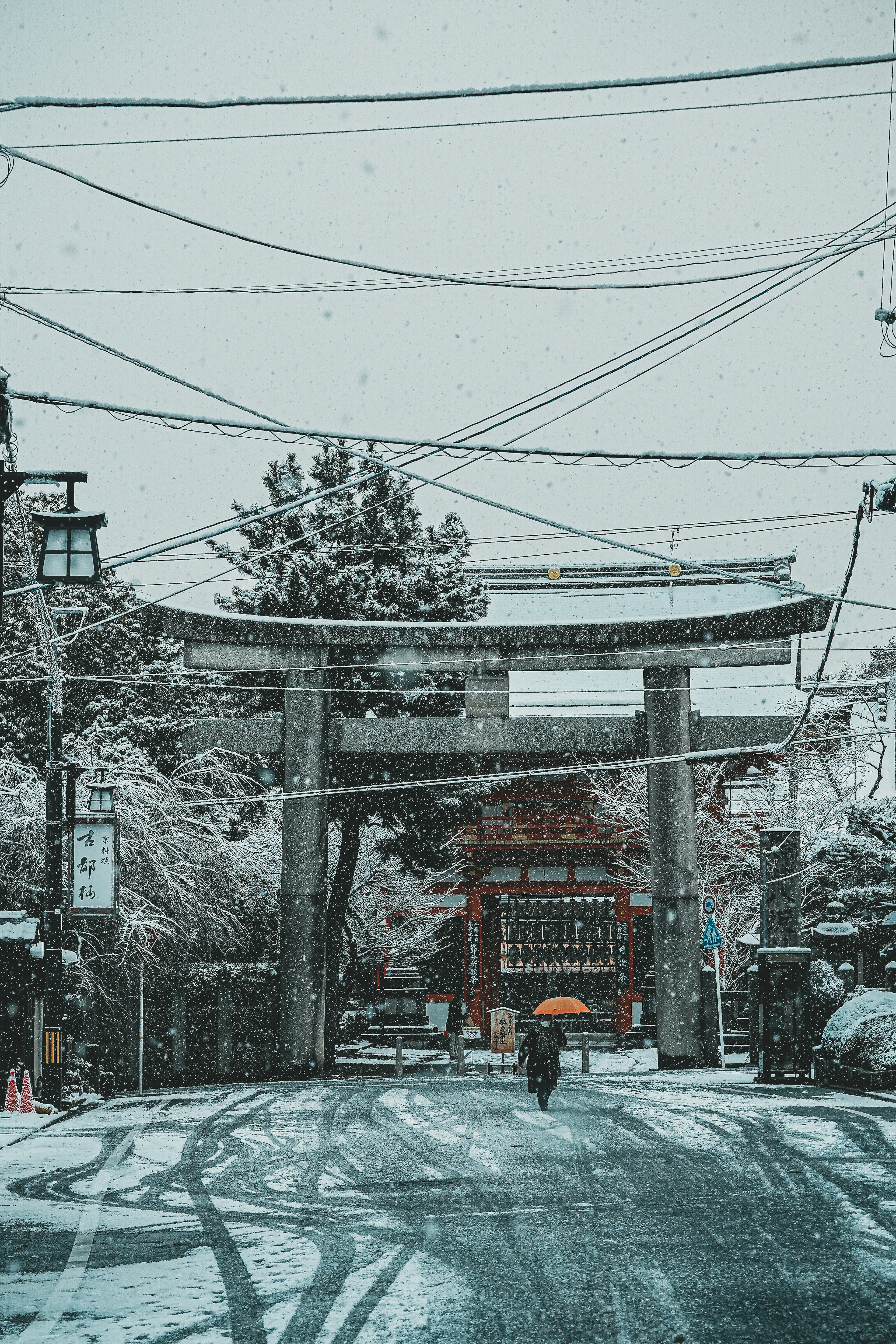 雪に覆われた神社の鳥居と静かな通りの風景