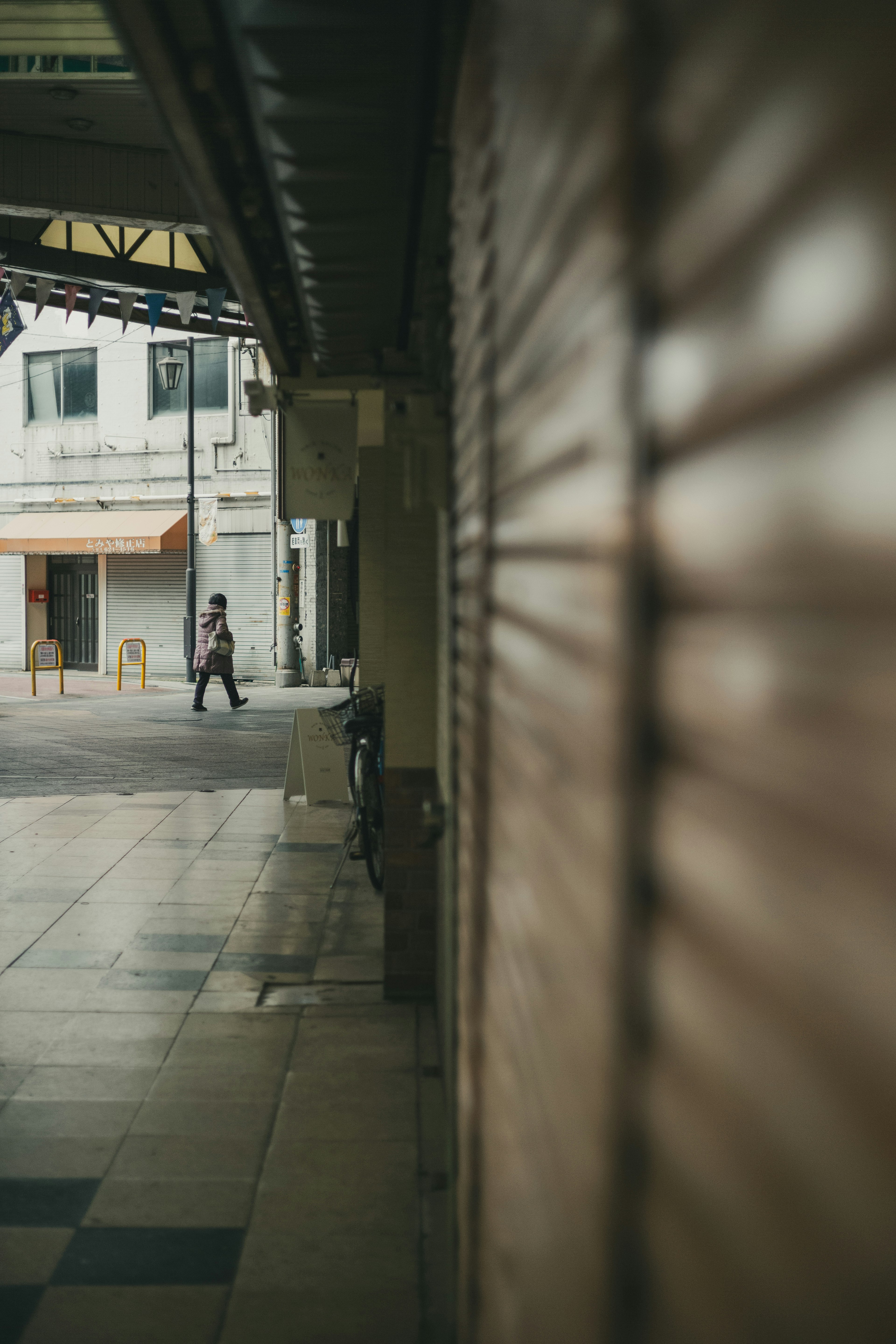 A person walking at a quiet street corner with closed shops