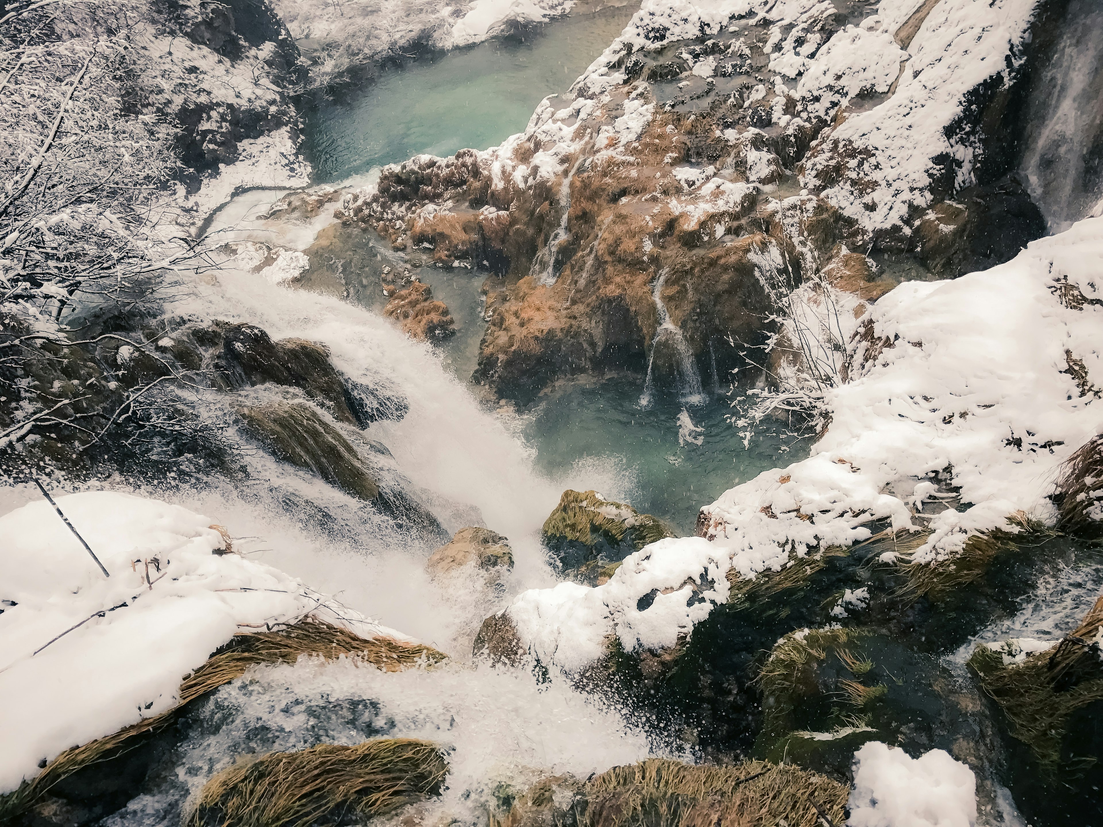 Vue d'en haut d'une cascade recouverte de neige avec de l'eau bleue qui s'écoule